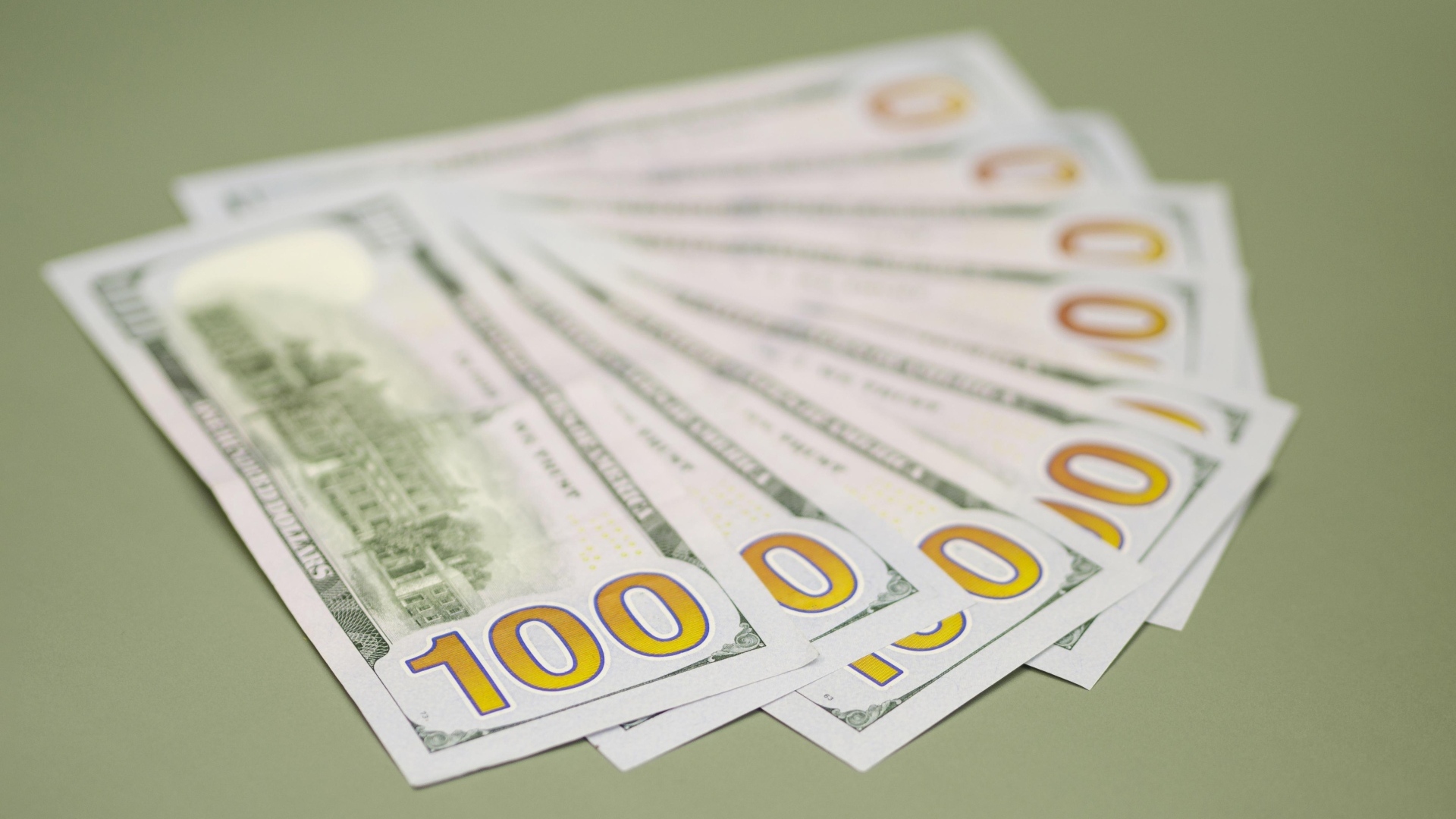 Пачка стодолларовых купюр на зеленом фоне