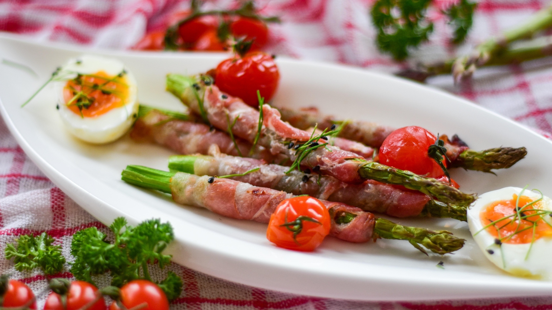 Спаржа в беконе на тарелке с вареными яйцами