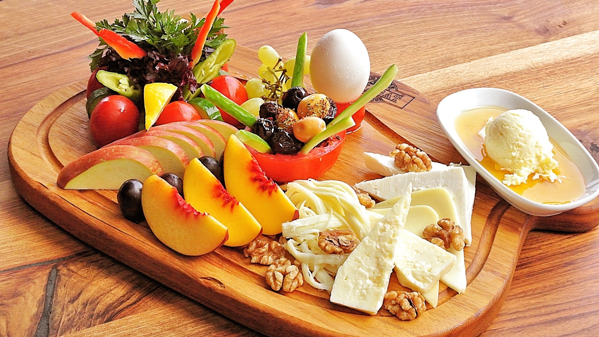 Сыр на доске с фруктами и салатом