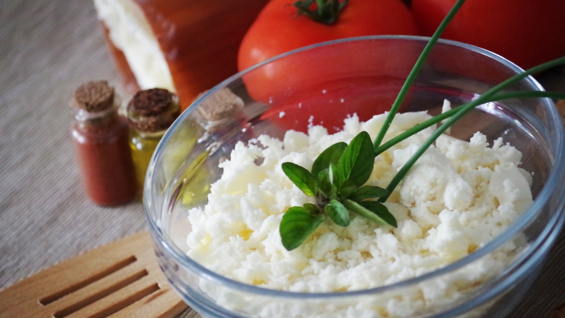 Творог в тарелке на столе с помидорами