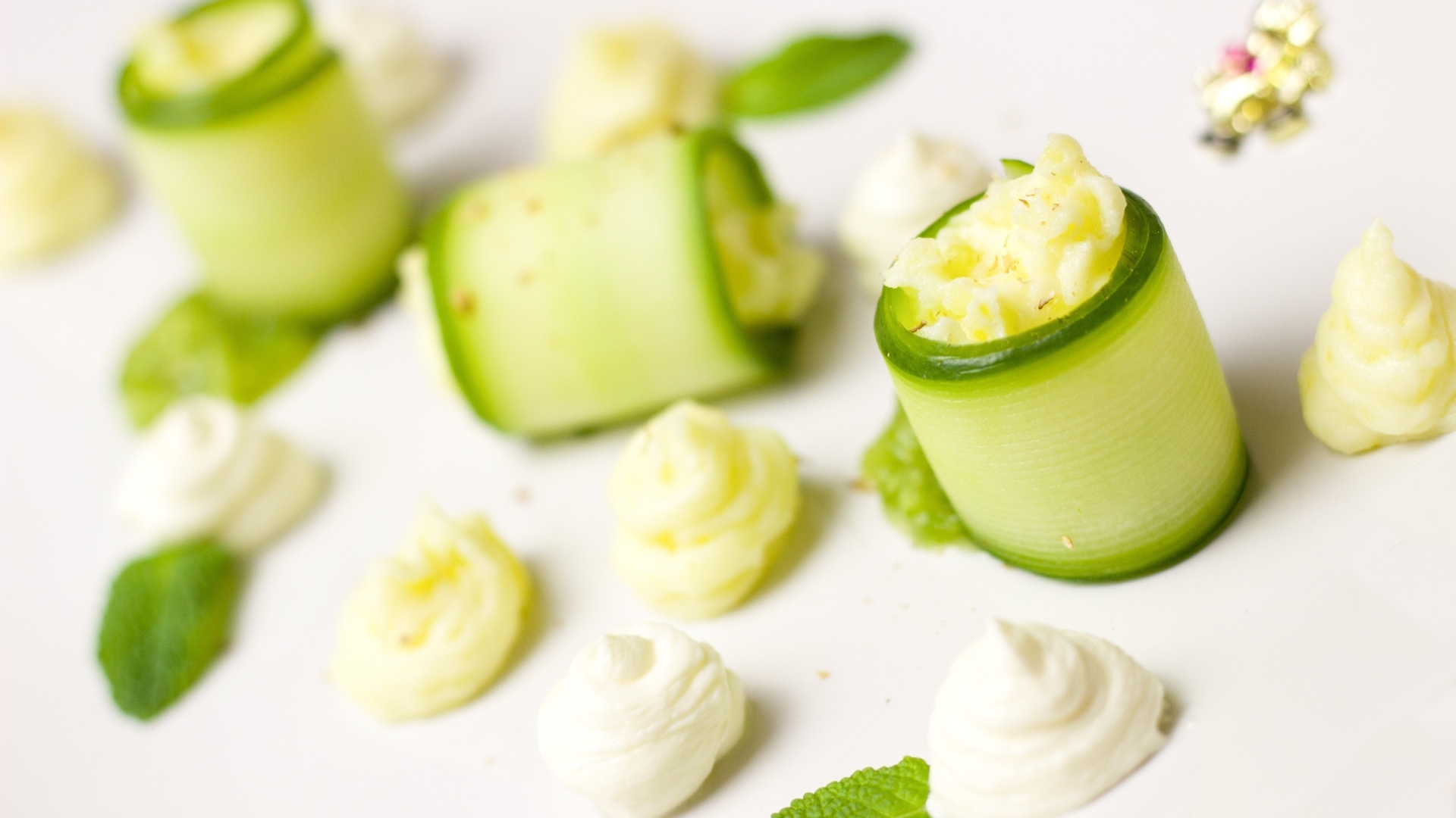 Рулетики из огурца с кремом на белом фоне
