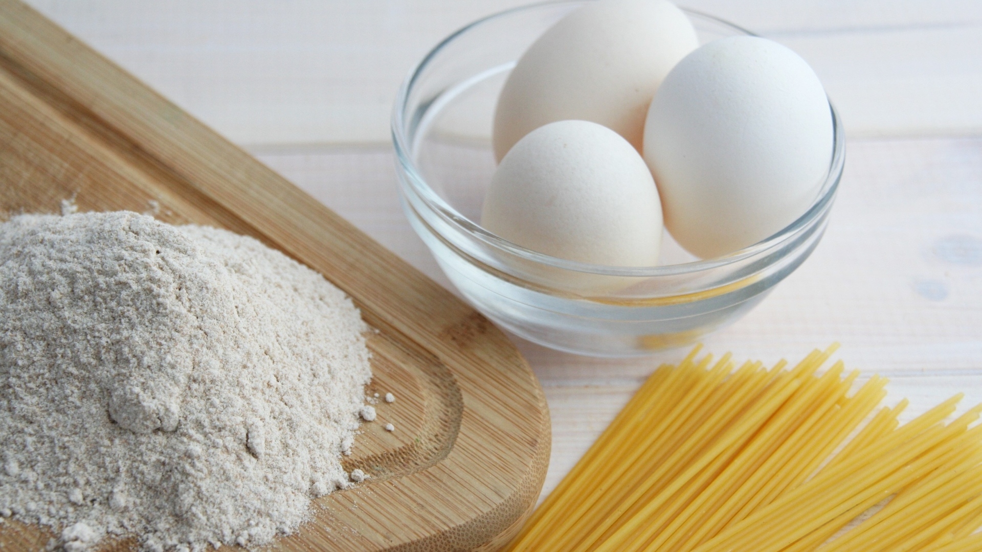 Яйца на столе с мукой и спагетти