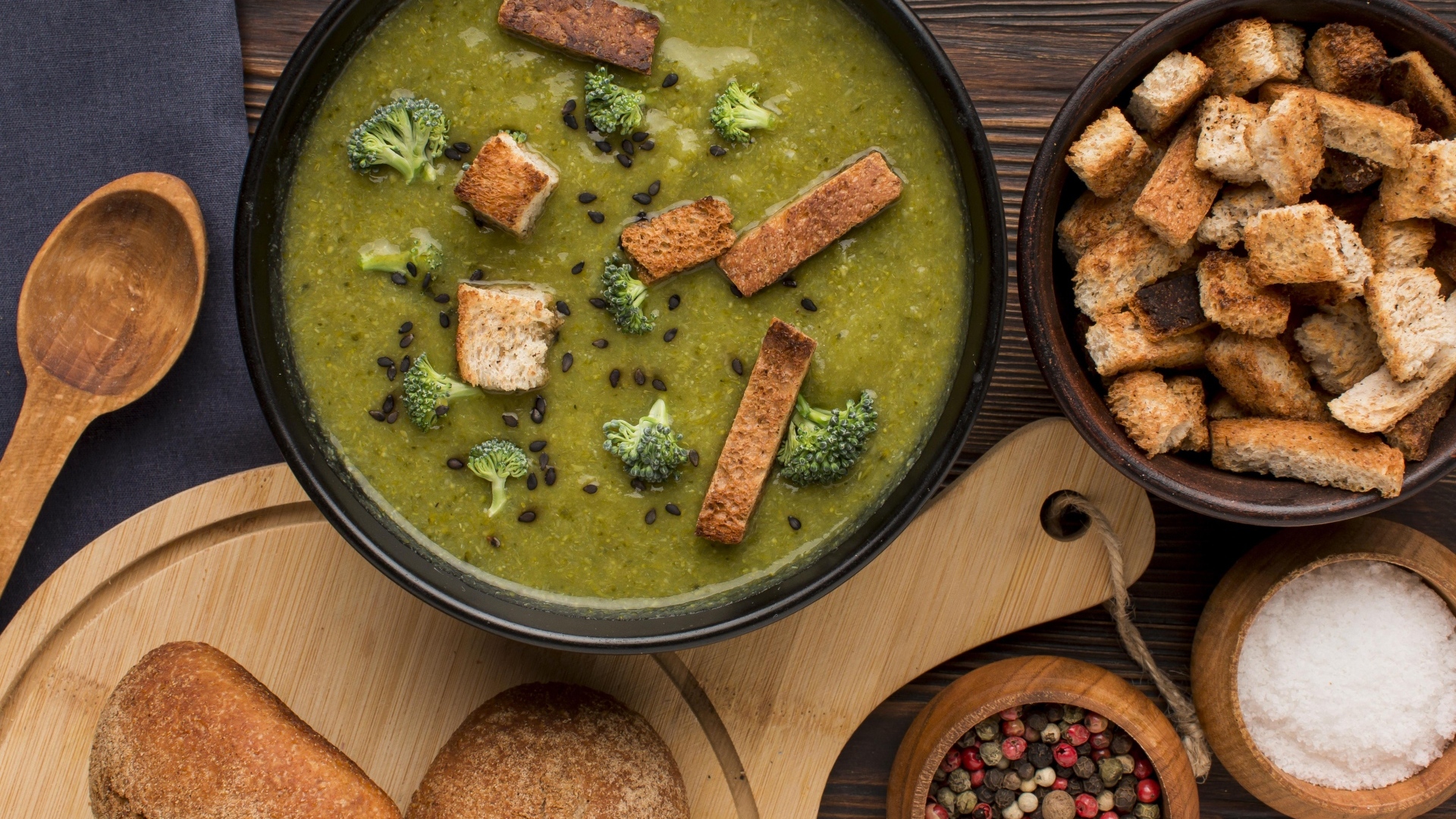 Зеленый суп пюре на столе с сухариками и перцем