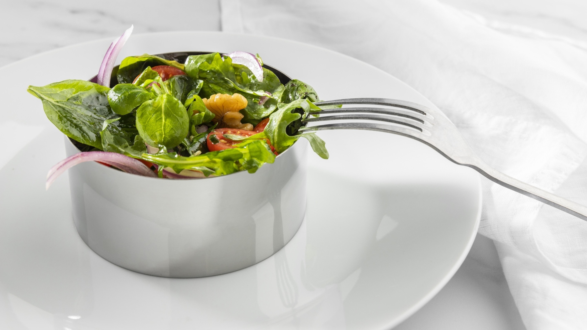 Зеленый салат с орехами на большой белой тарелке