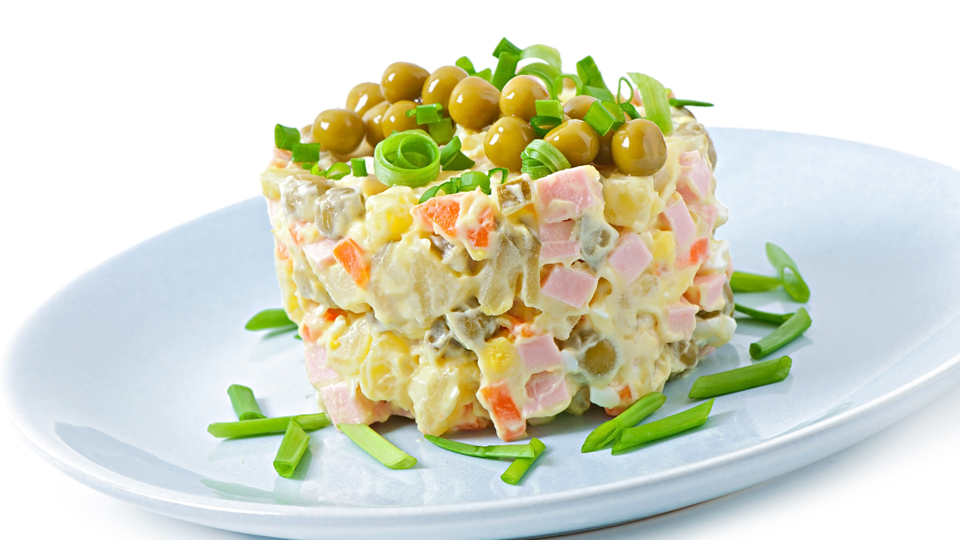 Салат оливье с зеленым горошком на тарелке 