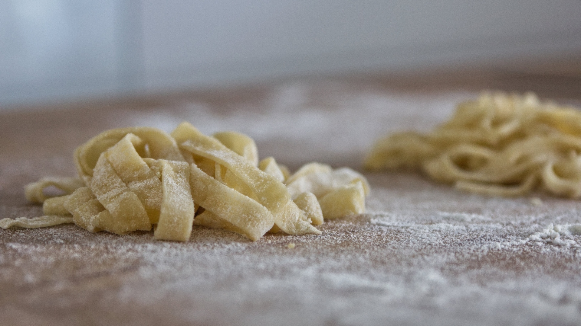 Сырое тесто для лапши на покрытом мукой столе