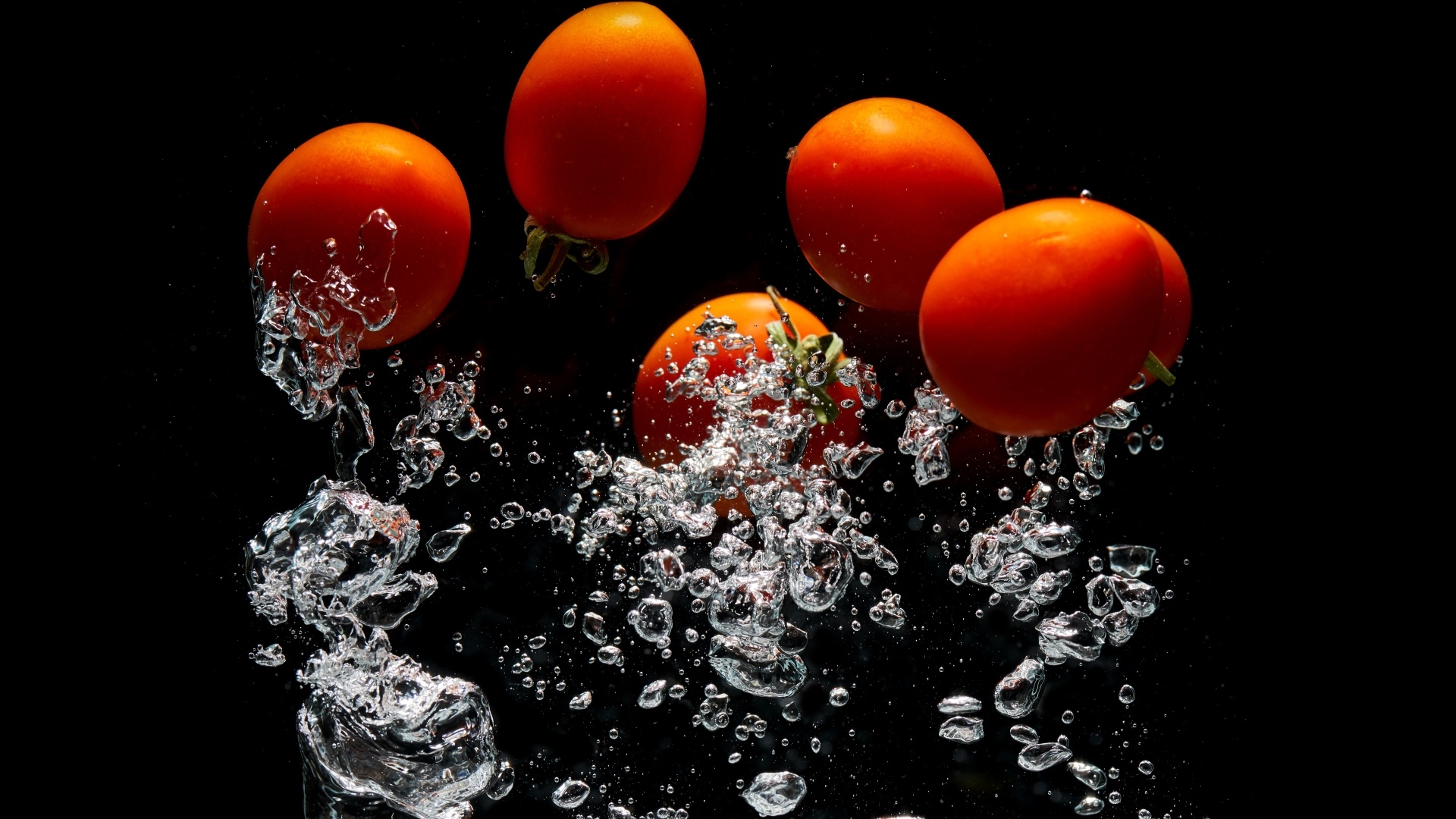 Красные помидоры в воде на черном фоне