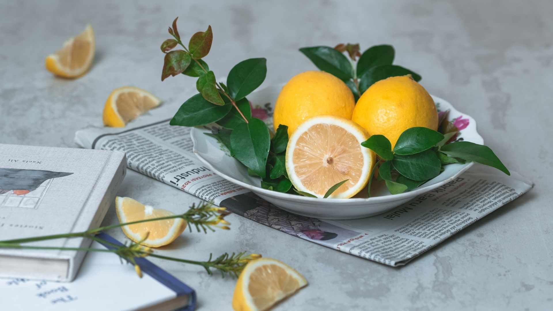 Лимоны на тарелке с зелеными листьями