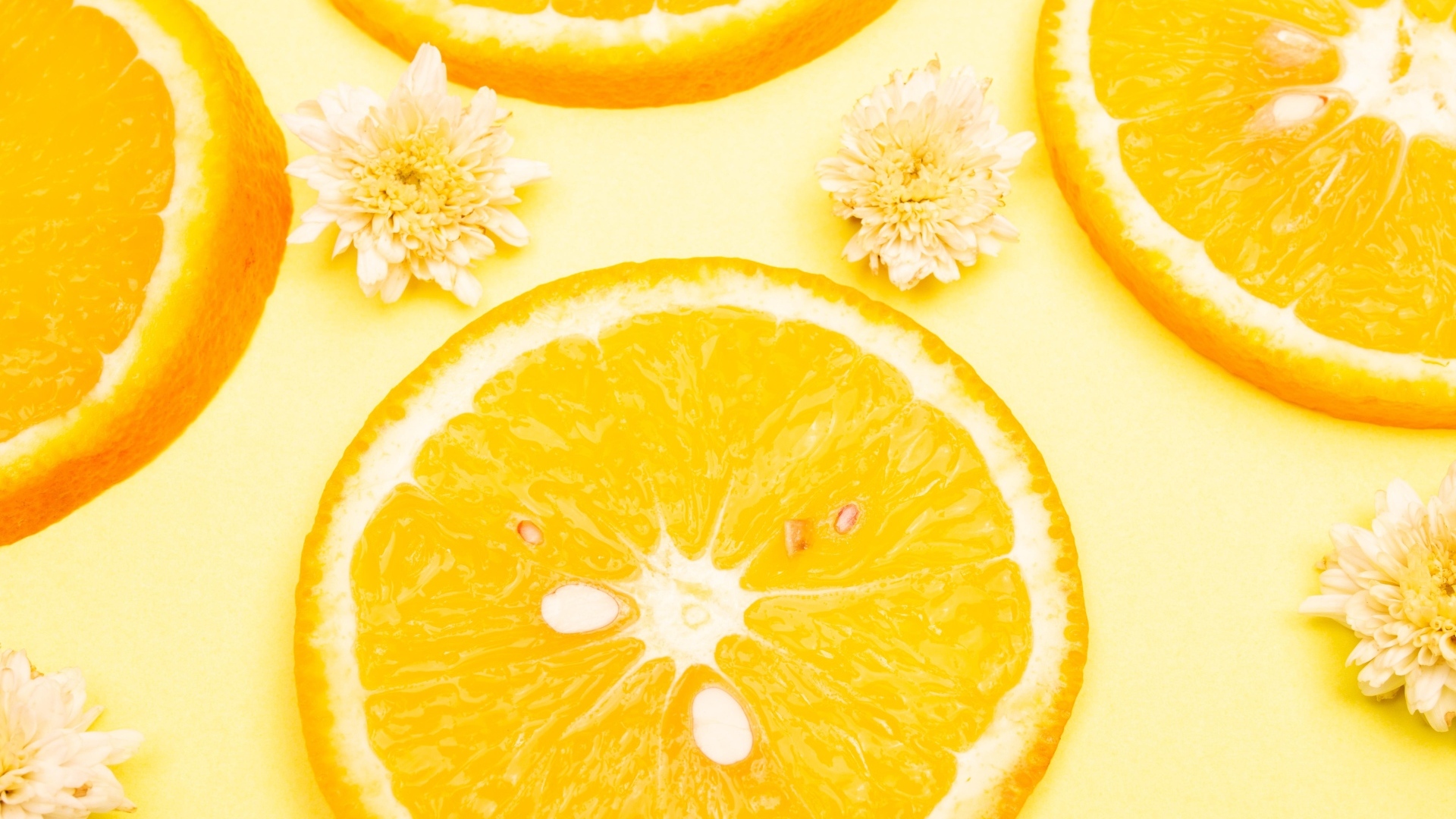 Апельсин с цветами хризантемы на желтом фоне