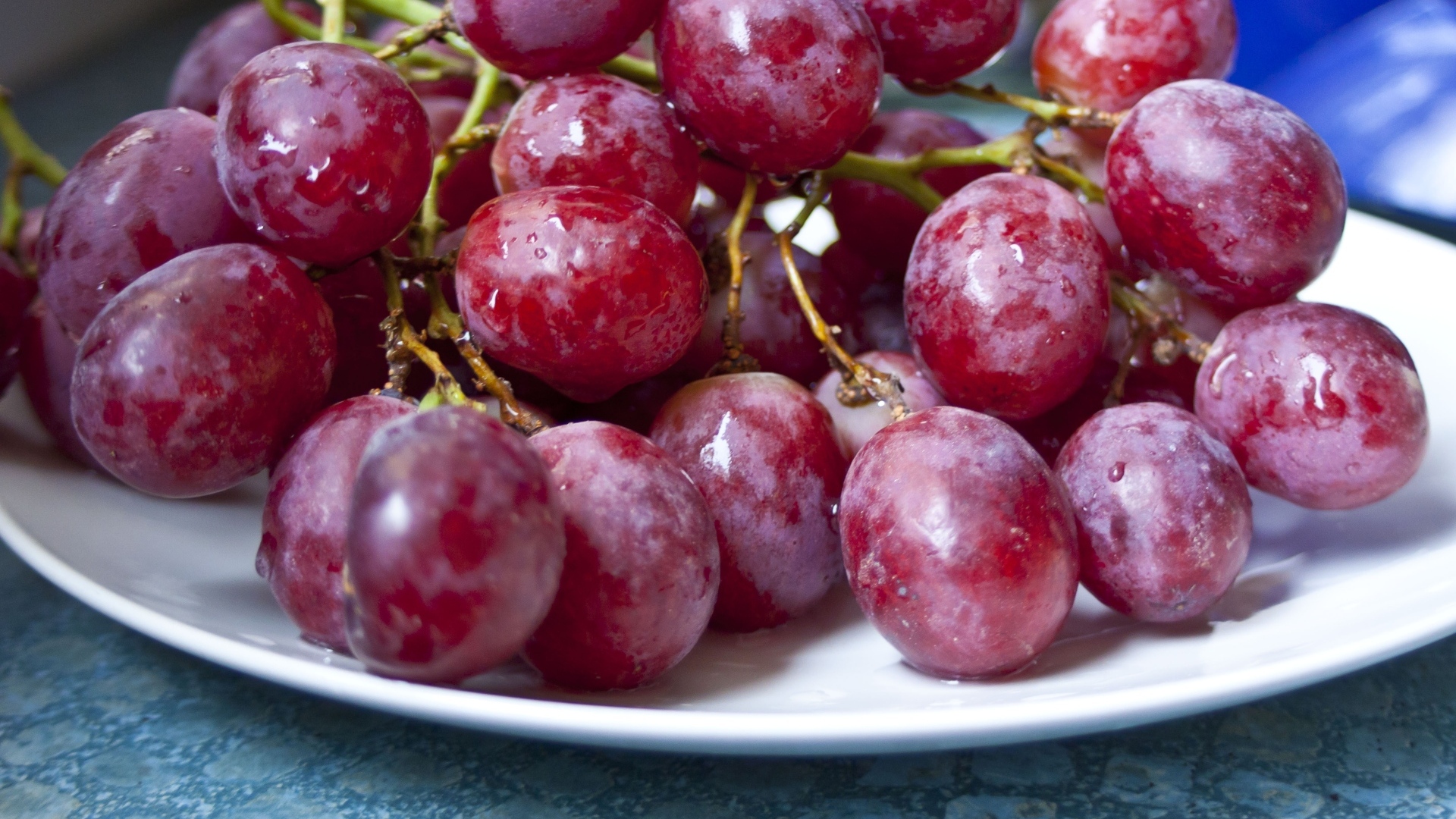 Спелый розовый виноград на белой тарелке