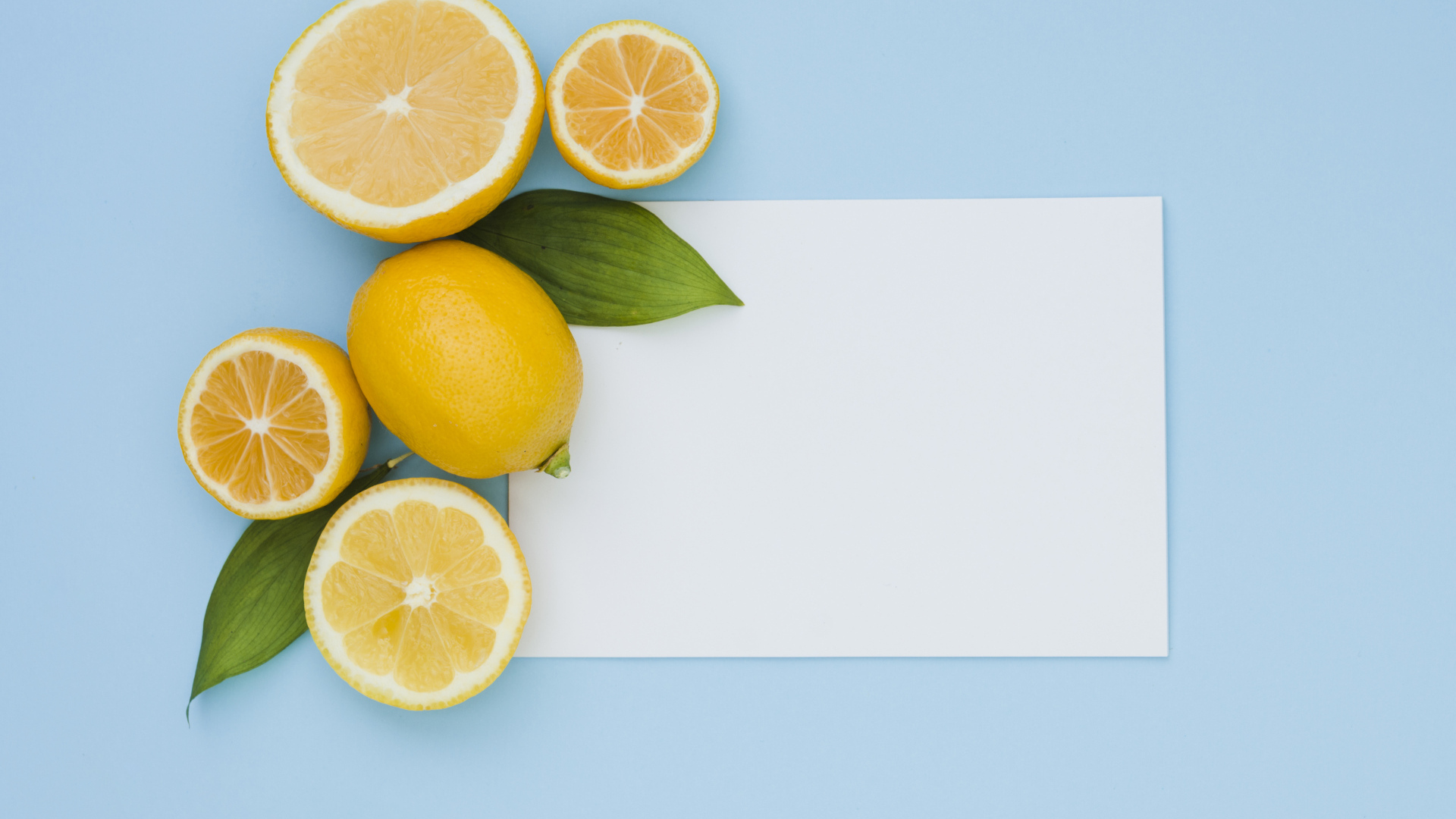 Белый лист бумаги с лимонами и апельсинами на голубом фоне