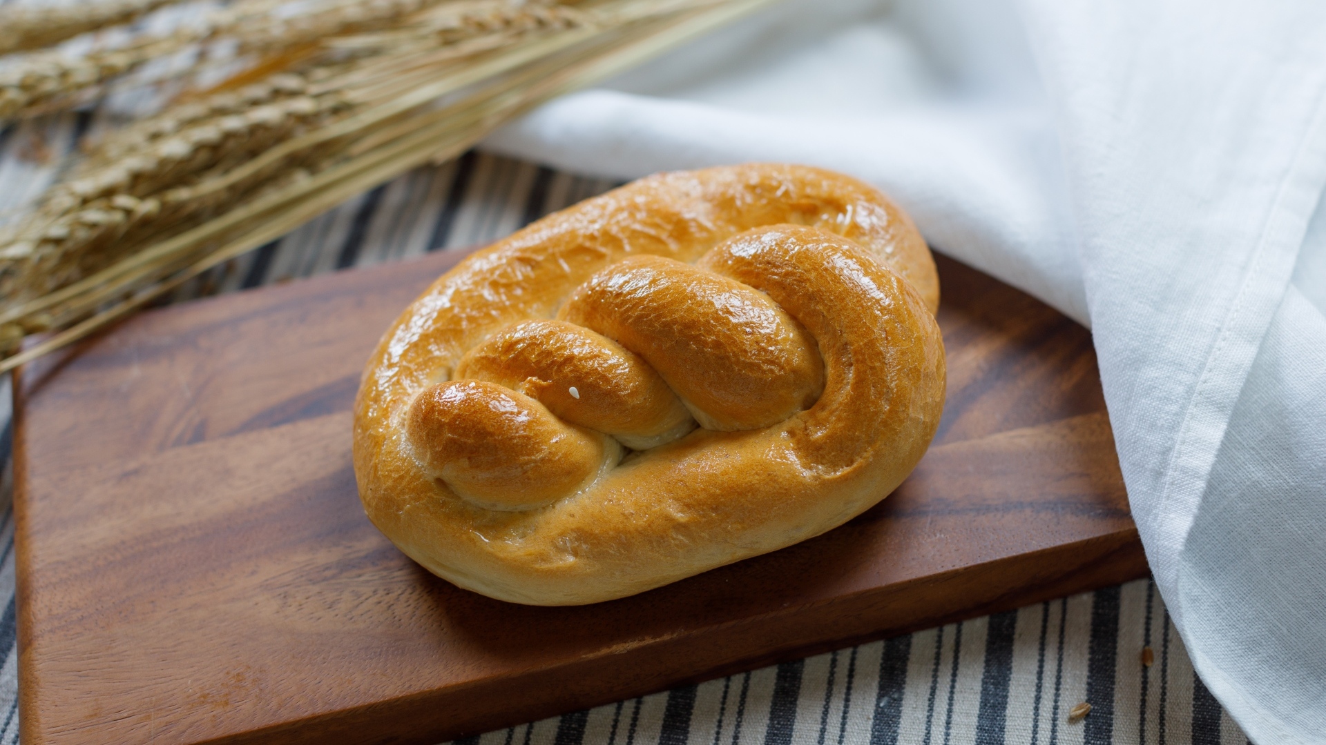 Булочка на столе с колосьями пшеницы