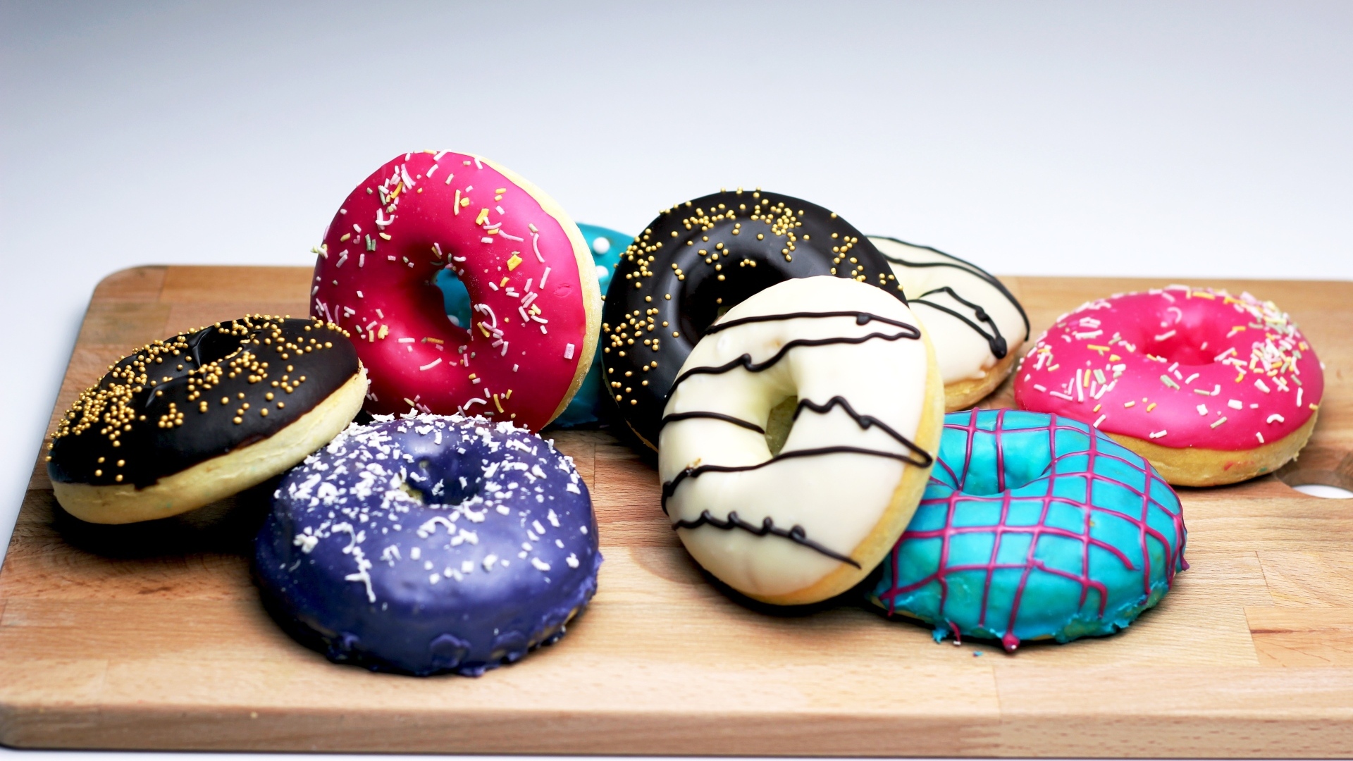 Аппетитные разноцветные пончики на деревянной доске