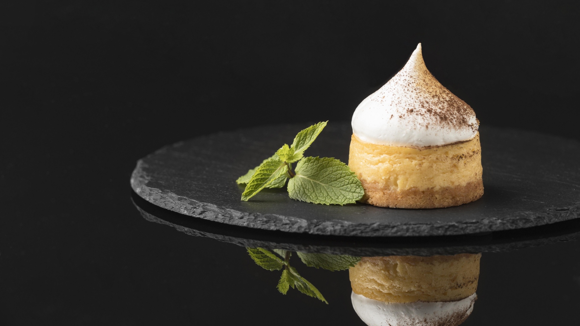 Десерт с кремом и листьями мяты на черном фоне