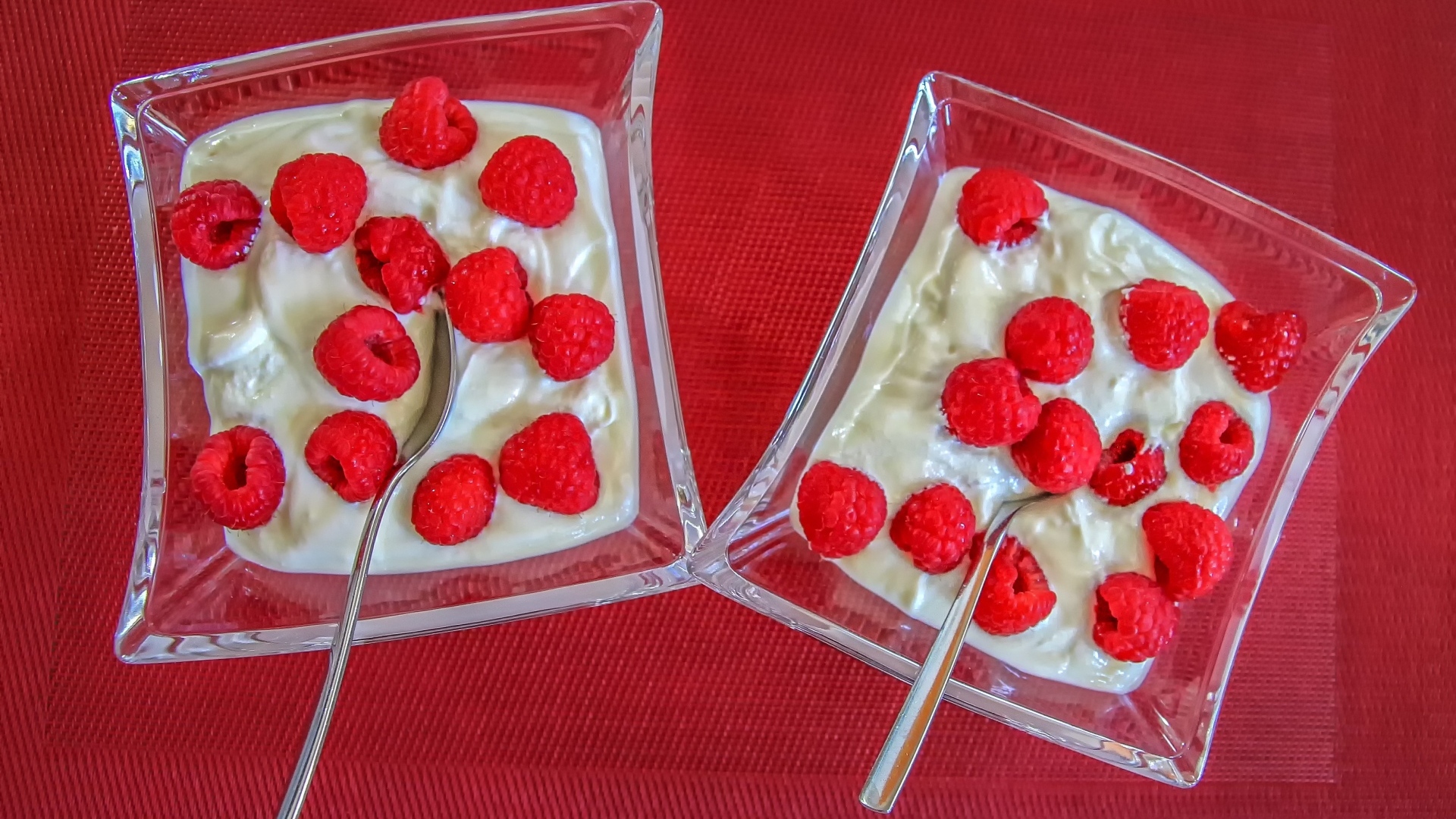 Десерт с ягодами малины на красном столе