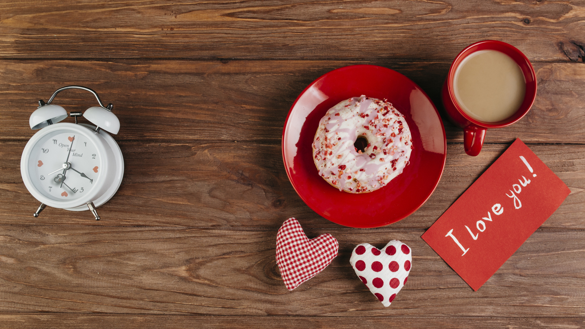 Пончик на столе с будильником, чашкой кофе и сердечками