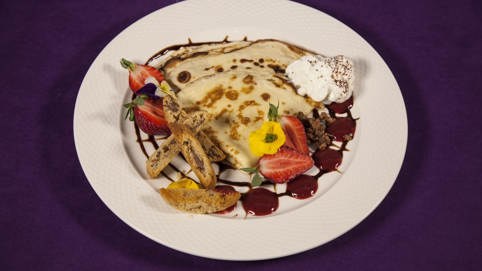 Тонкие блинчики с кремом и ягодами на тарелке