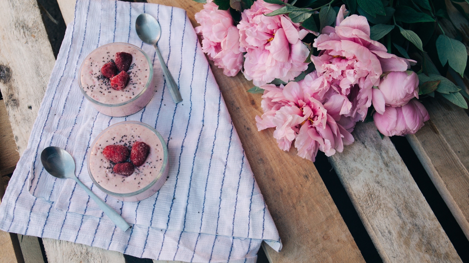 Два стакана с десертом на лавке с букетом пионов