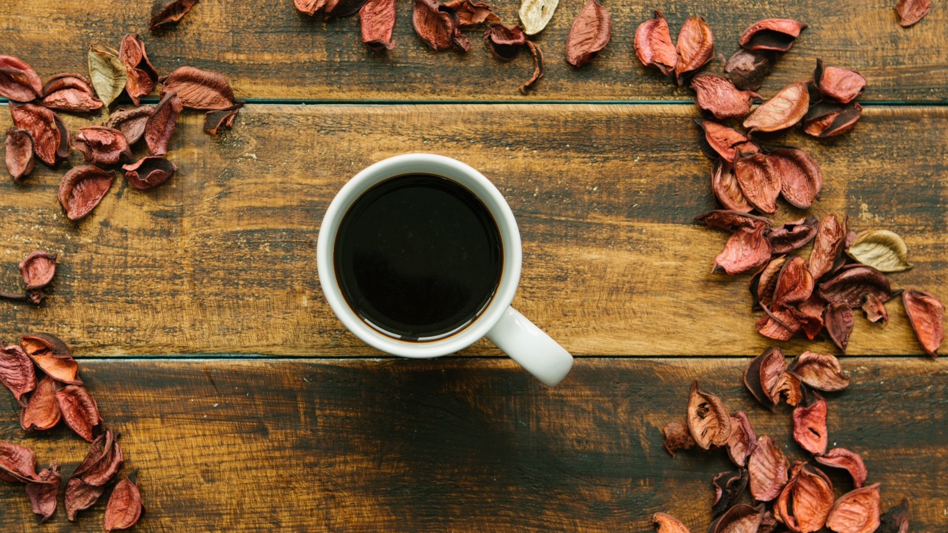 Чашка кофе с опавшими листьями на деревянном столе