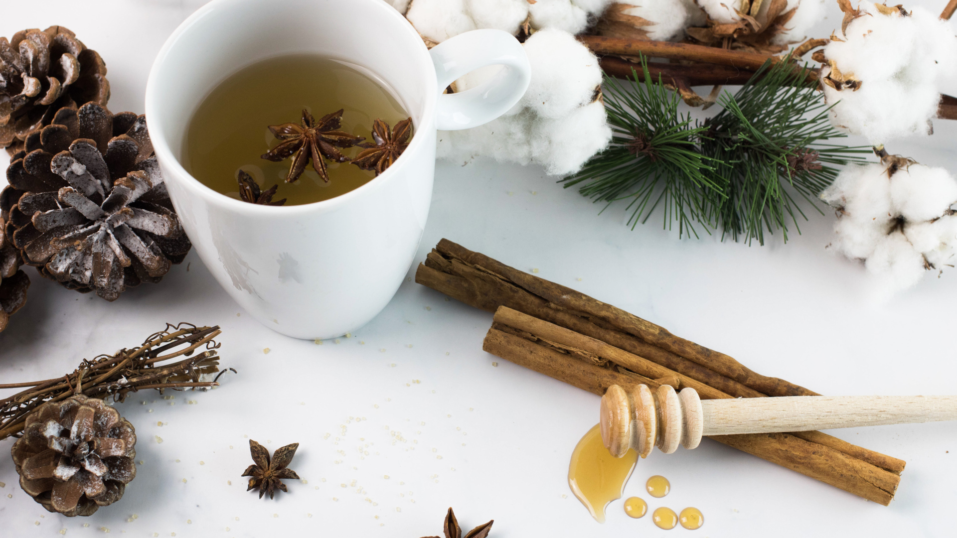 Чашка чая со специями на столе с хлопком и шишками