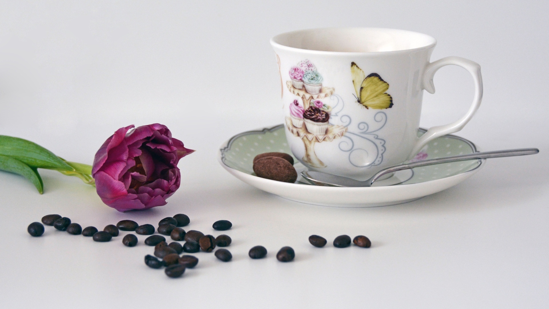 Чашка на столе с кофейными зернами и тюльпаном