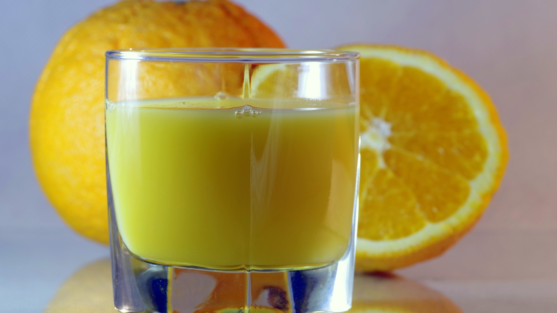 Оранжевый апельсиновый сок в стакане на столе с плодами