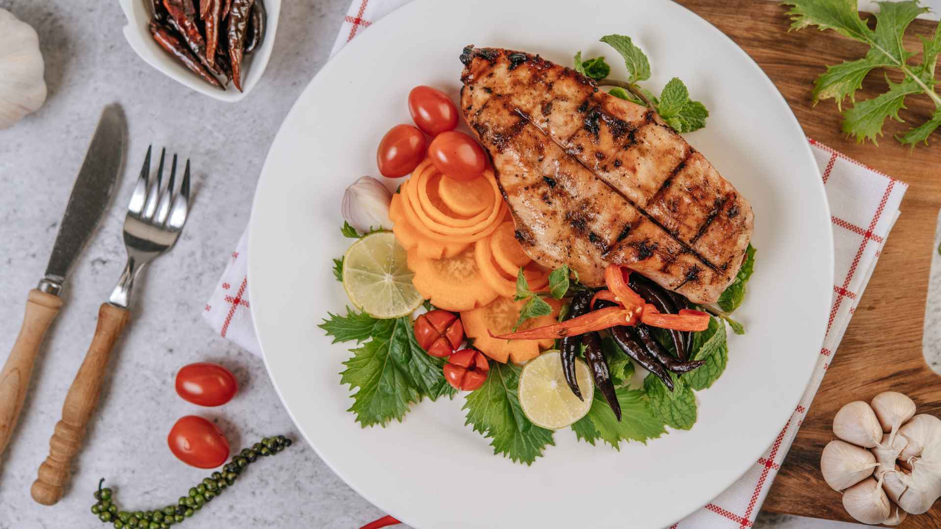 Кусок жареной курицы на большой белой тарелке с овощами