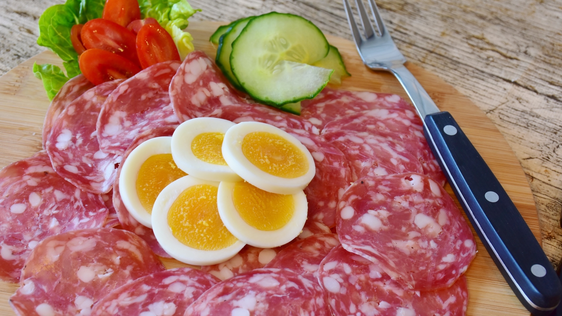 Колбаса салями на доске с вареными яйцами и овощами