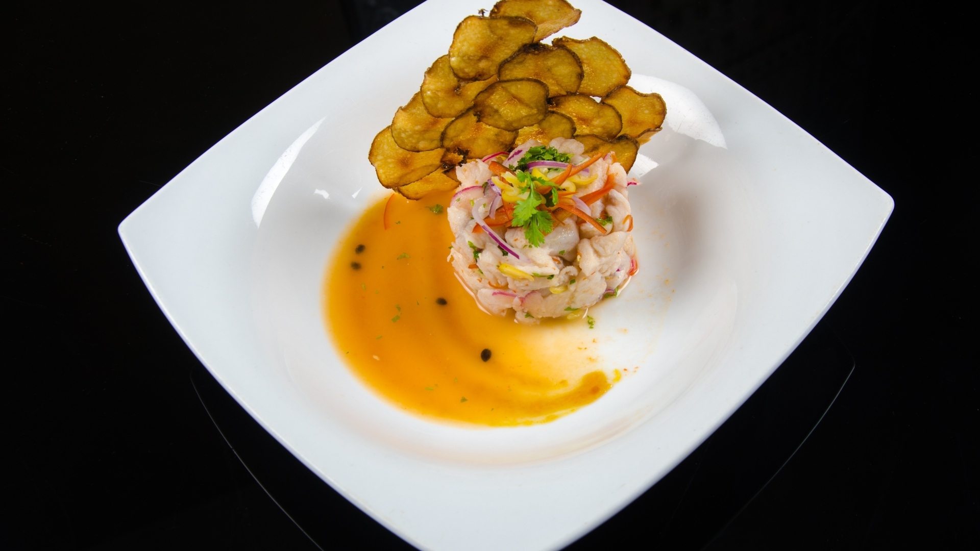 Морепродукты с соусом на большой белой тарелке на черном фоне