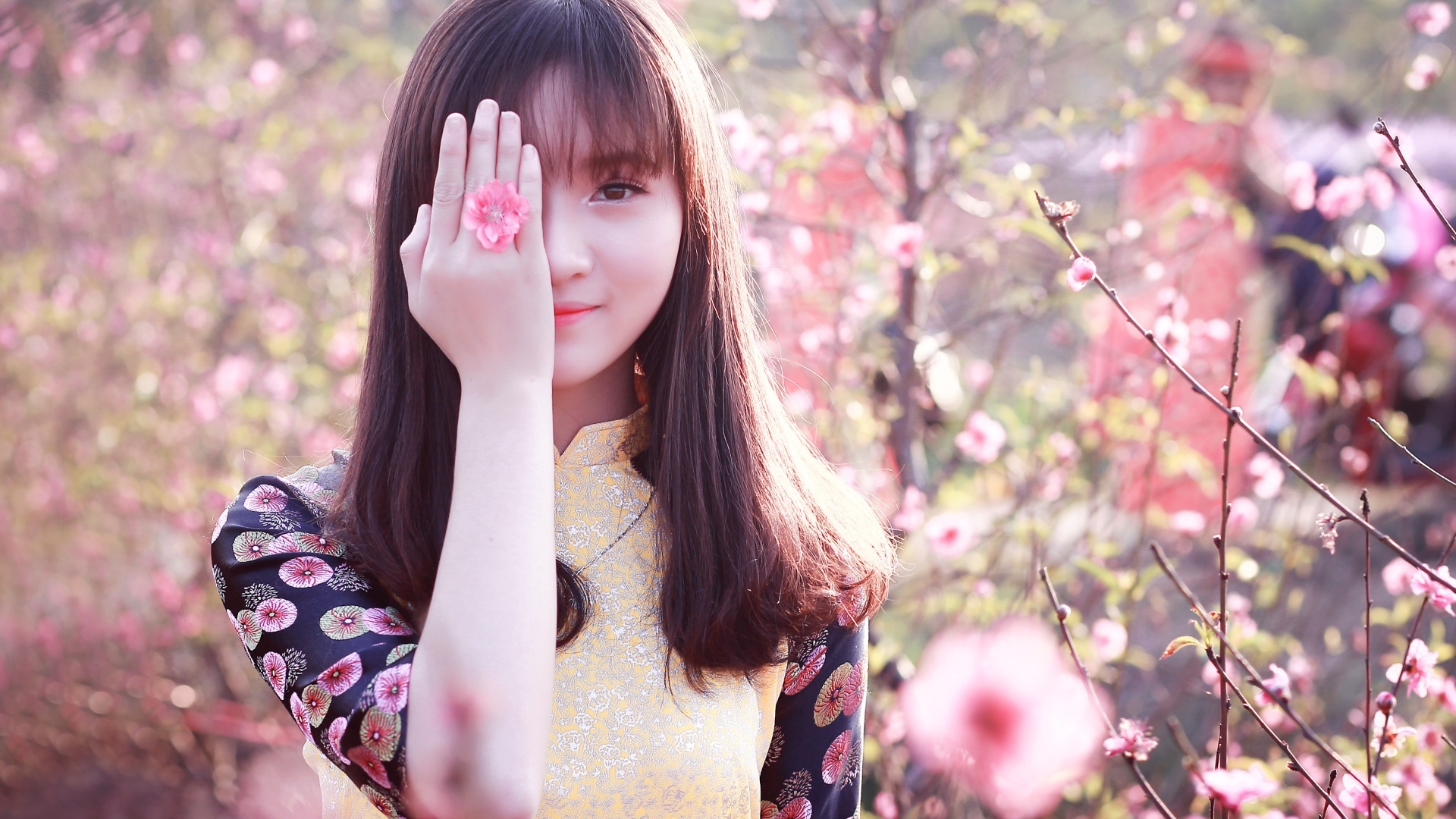 Девушка азиатка закрыла глаз рукой