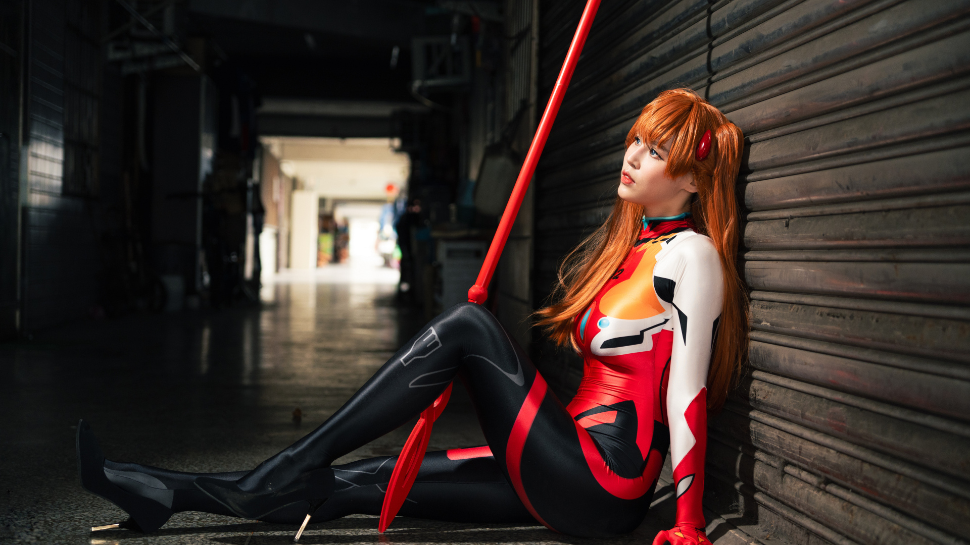 Девушка азиатка в костюме сидит у стены