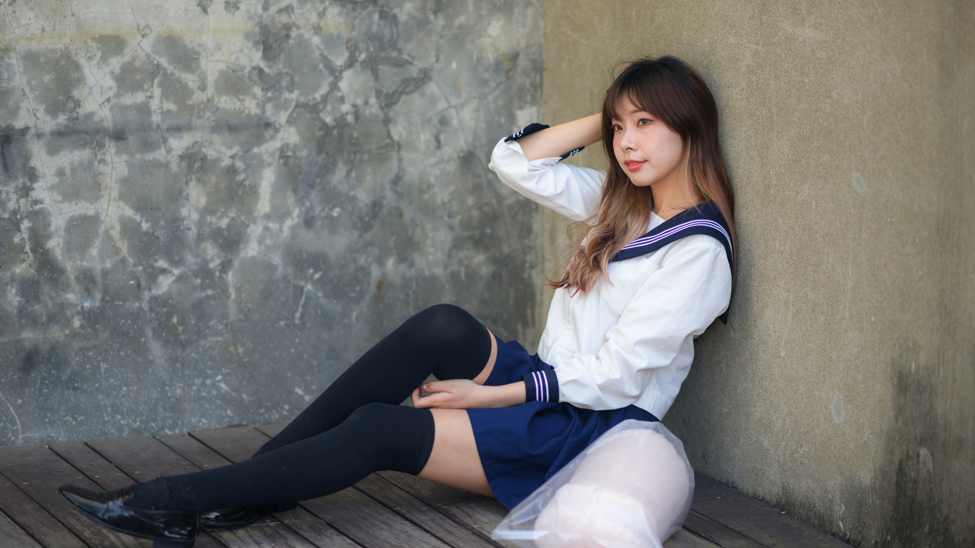 Азиатка в черных чулках сидит у стены