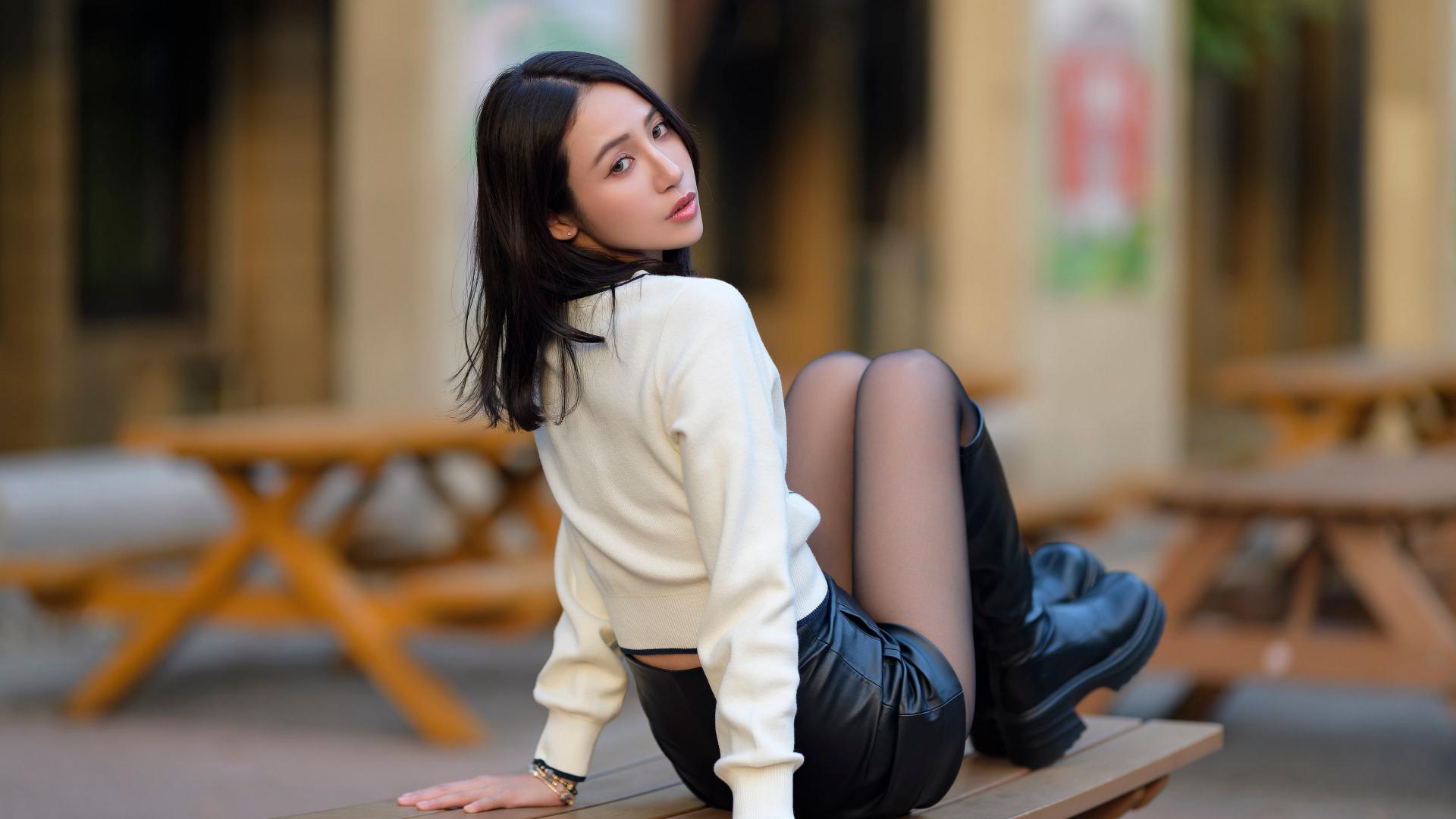 Азиатка в сапогах сидит на столе