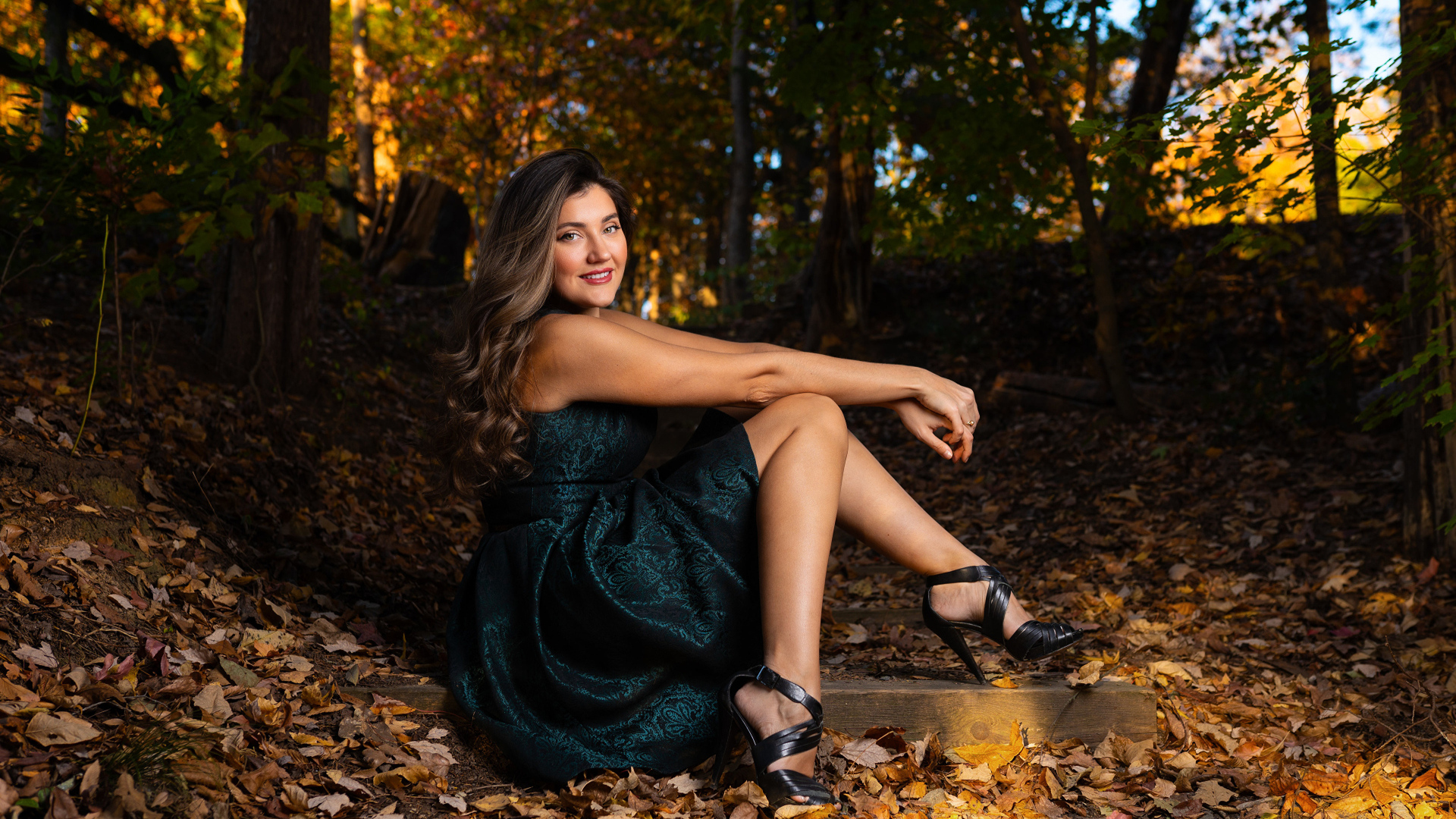 Красивая девушка в платье сидит на земле в осеннем парке