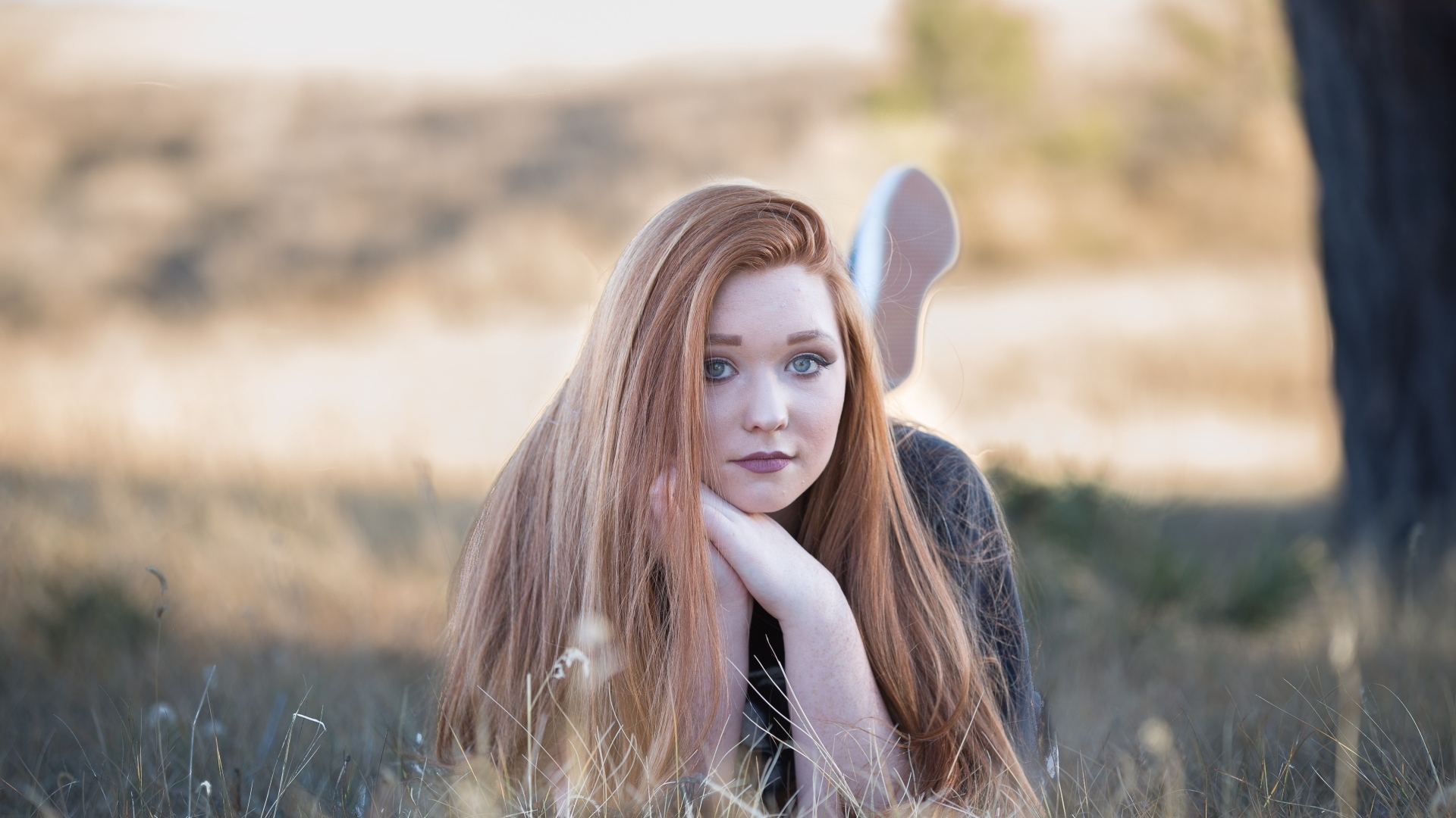 Красивая рыжеволосая девушка лежит на траве