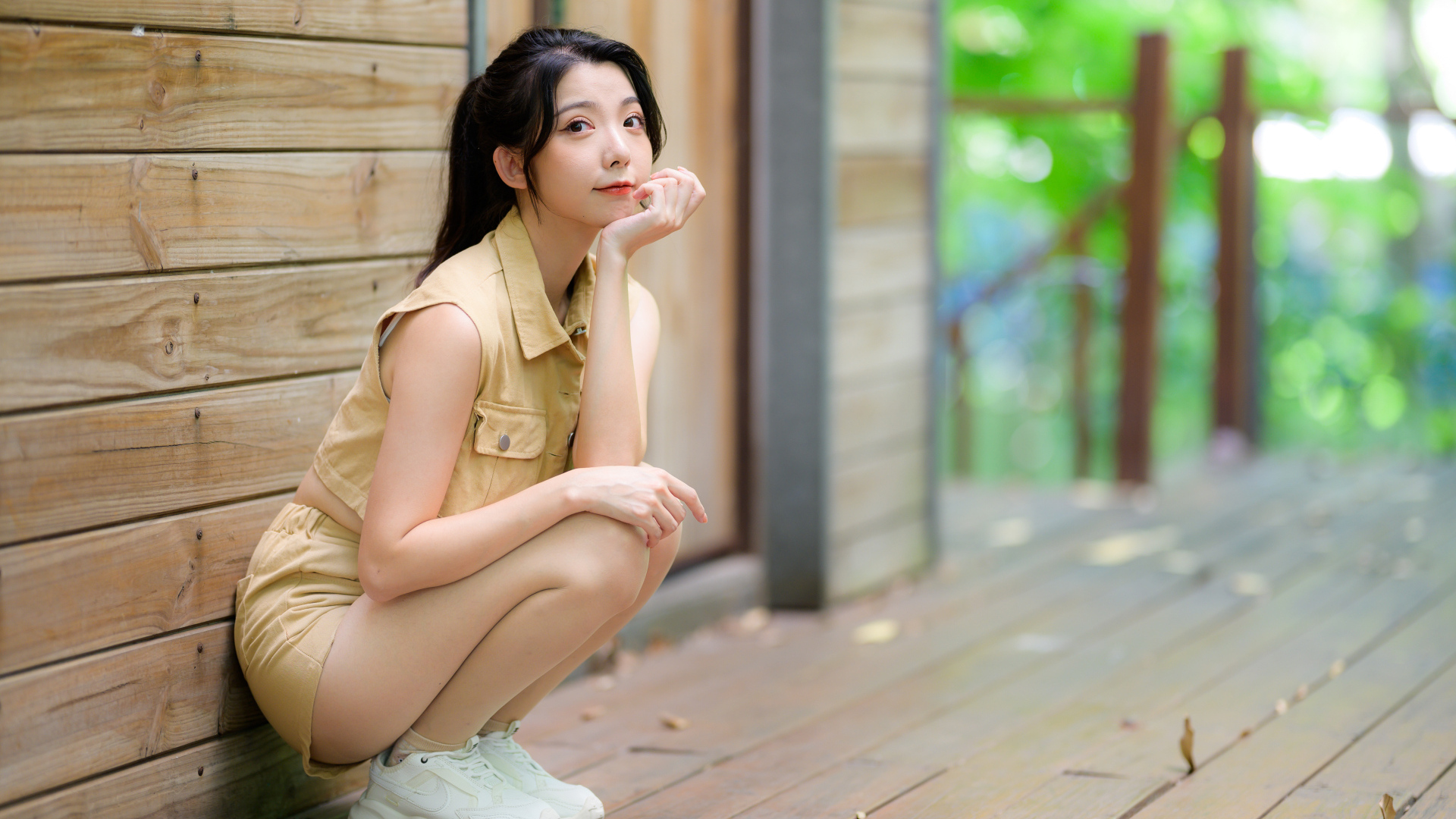 Милая азиатка сидит на корточках у стены