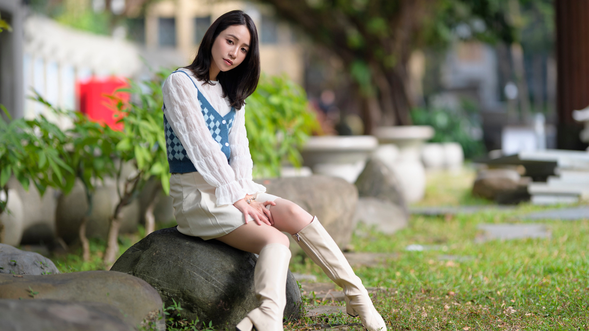 Милая девушка сидит на камне в парке