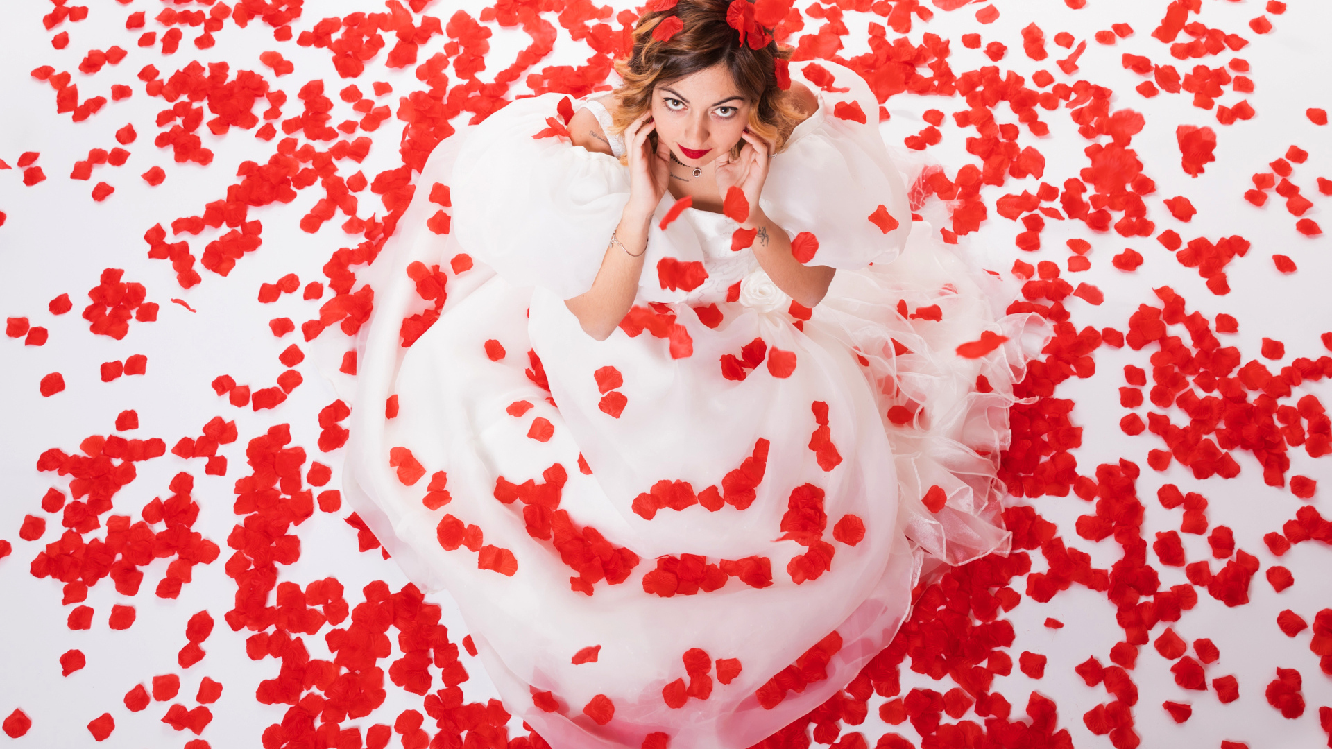 Девушка в белом платье сидит на лепестках розы