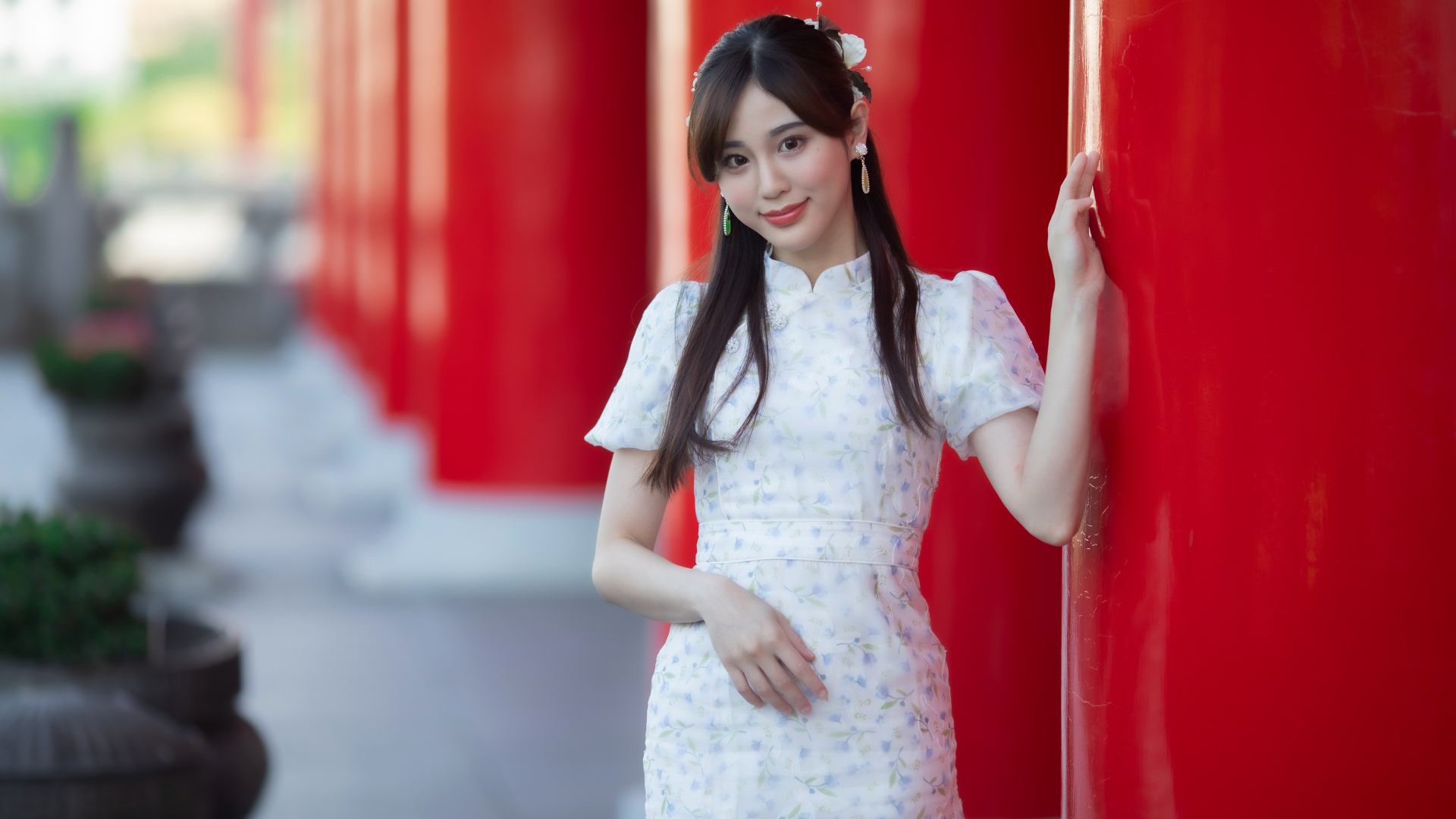 Длинноволосая азиатка позирует у красной колонны