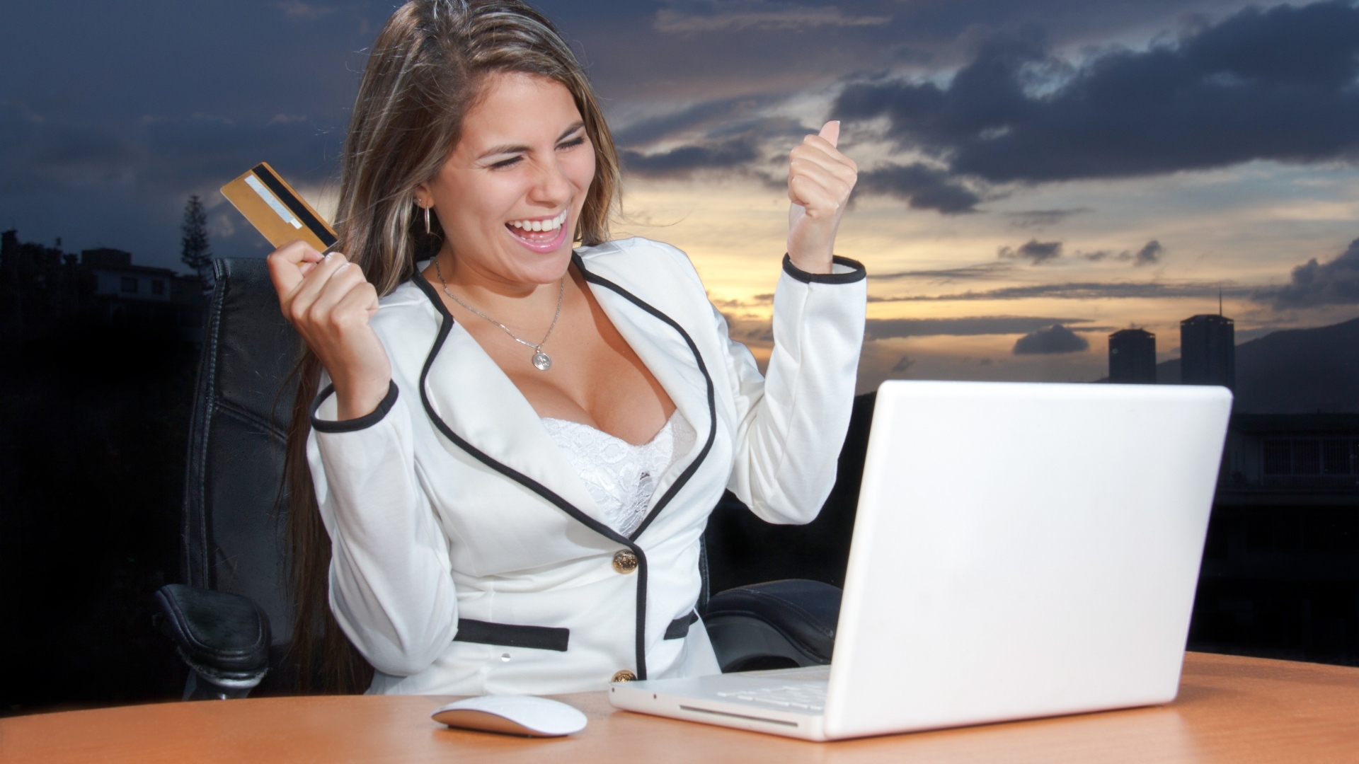 Довольная женщина с карточкой за столом с ноутбуком