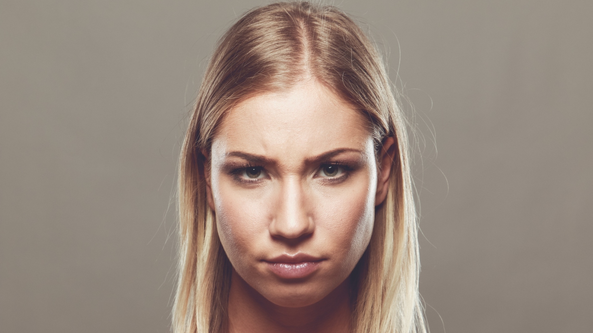 Серьезная девушка с короткой стрижкой на сером фоне