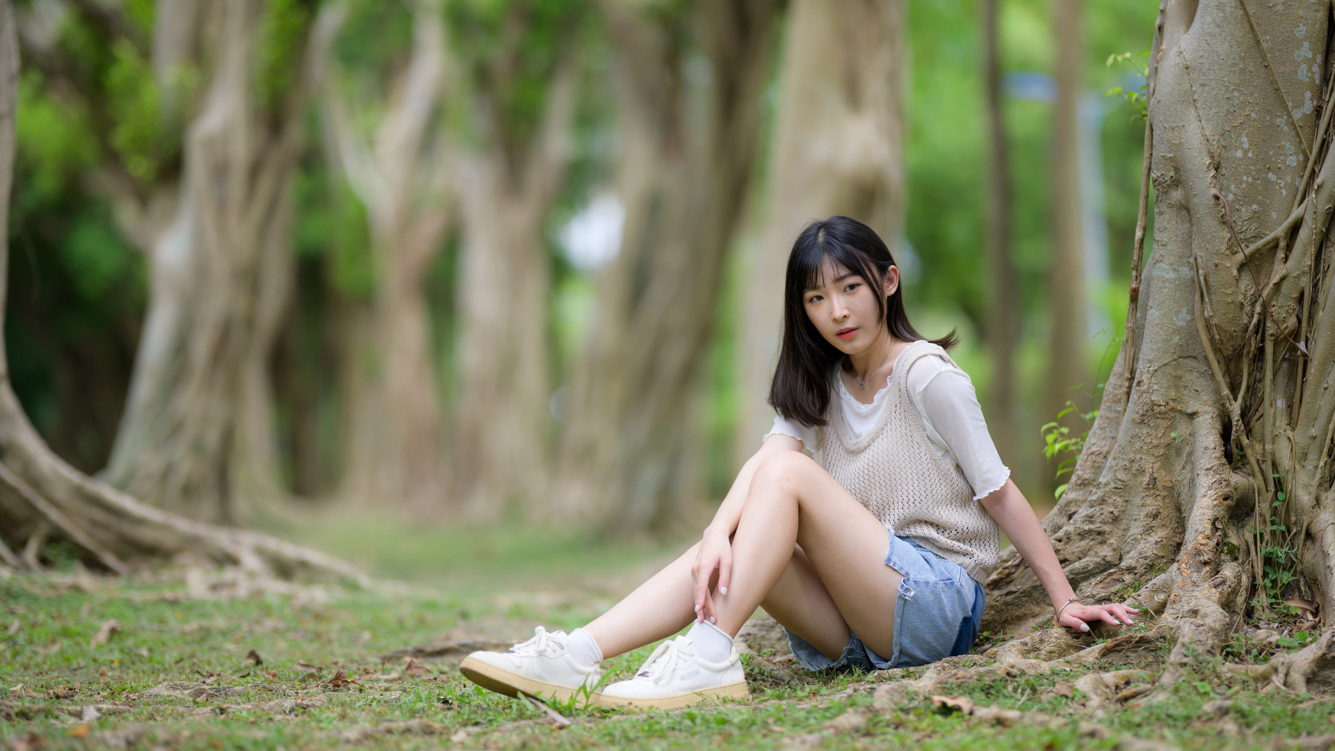 Молодая девушка азиатка сидит у дерева в парке