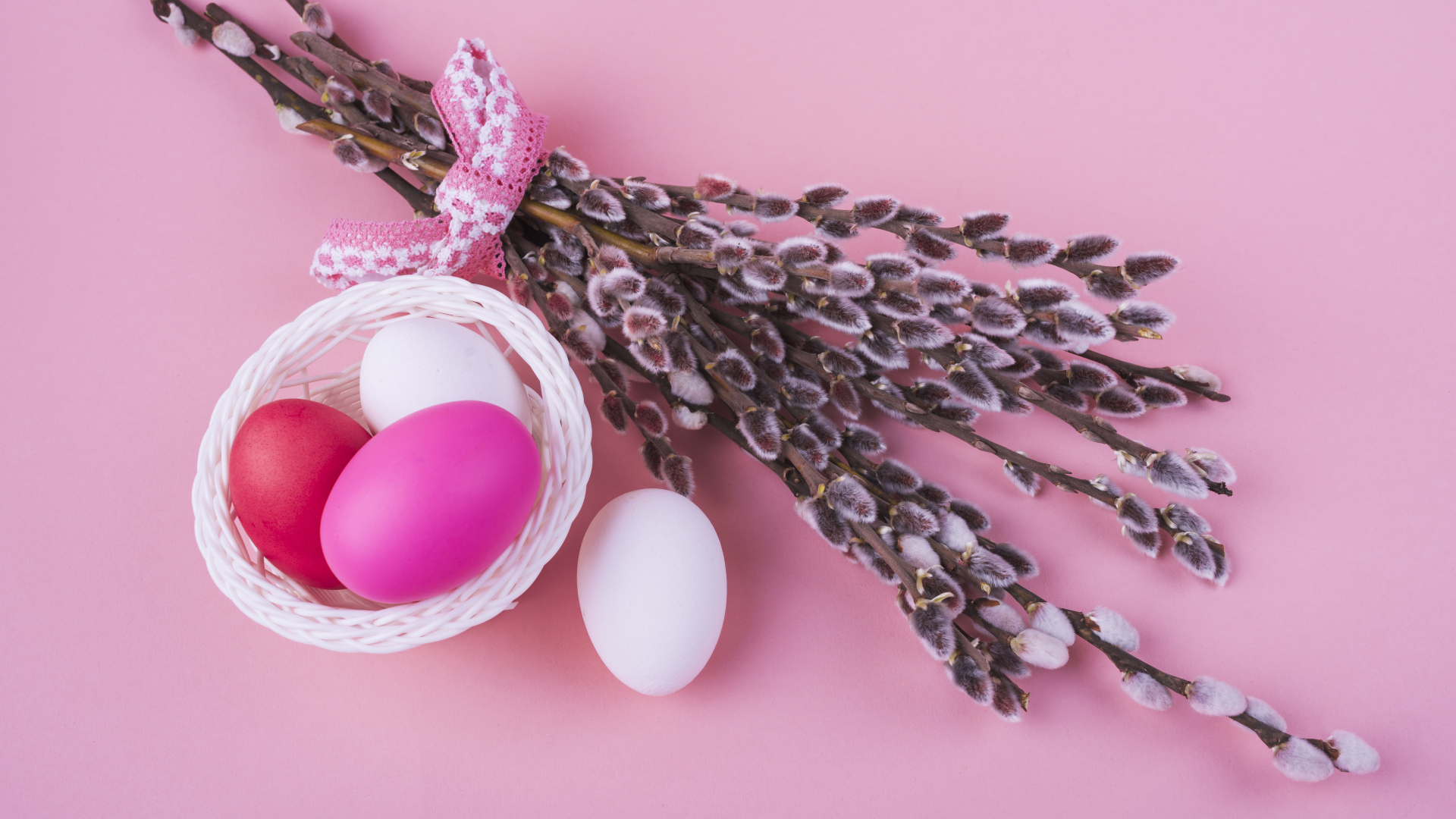 Ветки вербы с яйцами на розовом фоне