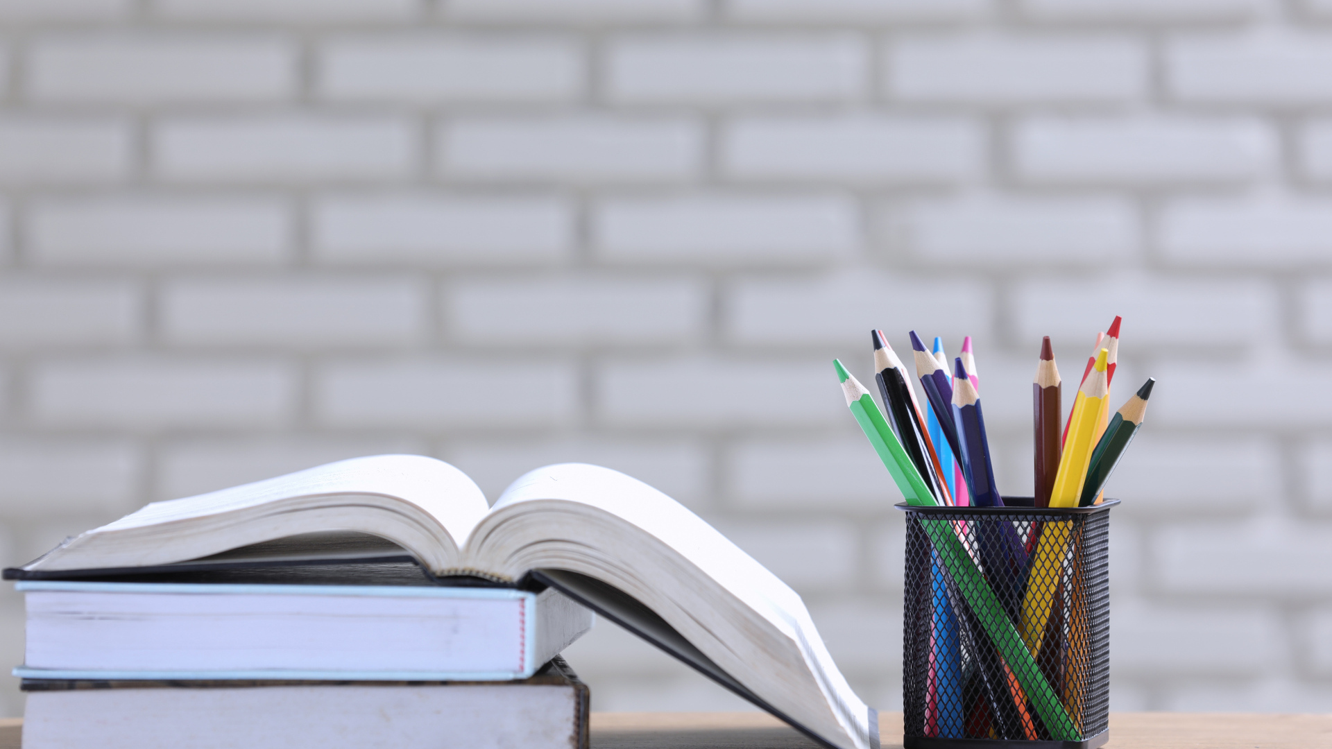 Разноцветные карандаши на столе с книгами 