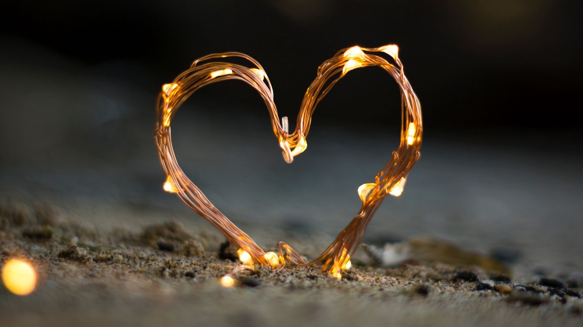 Сердце из гирлянды на песке