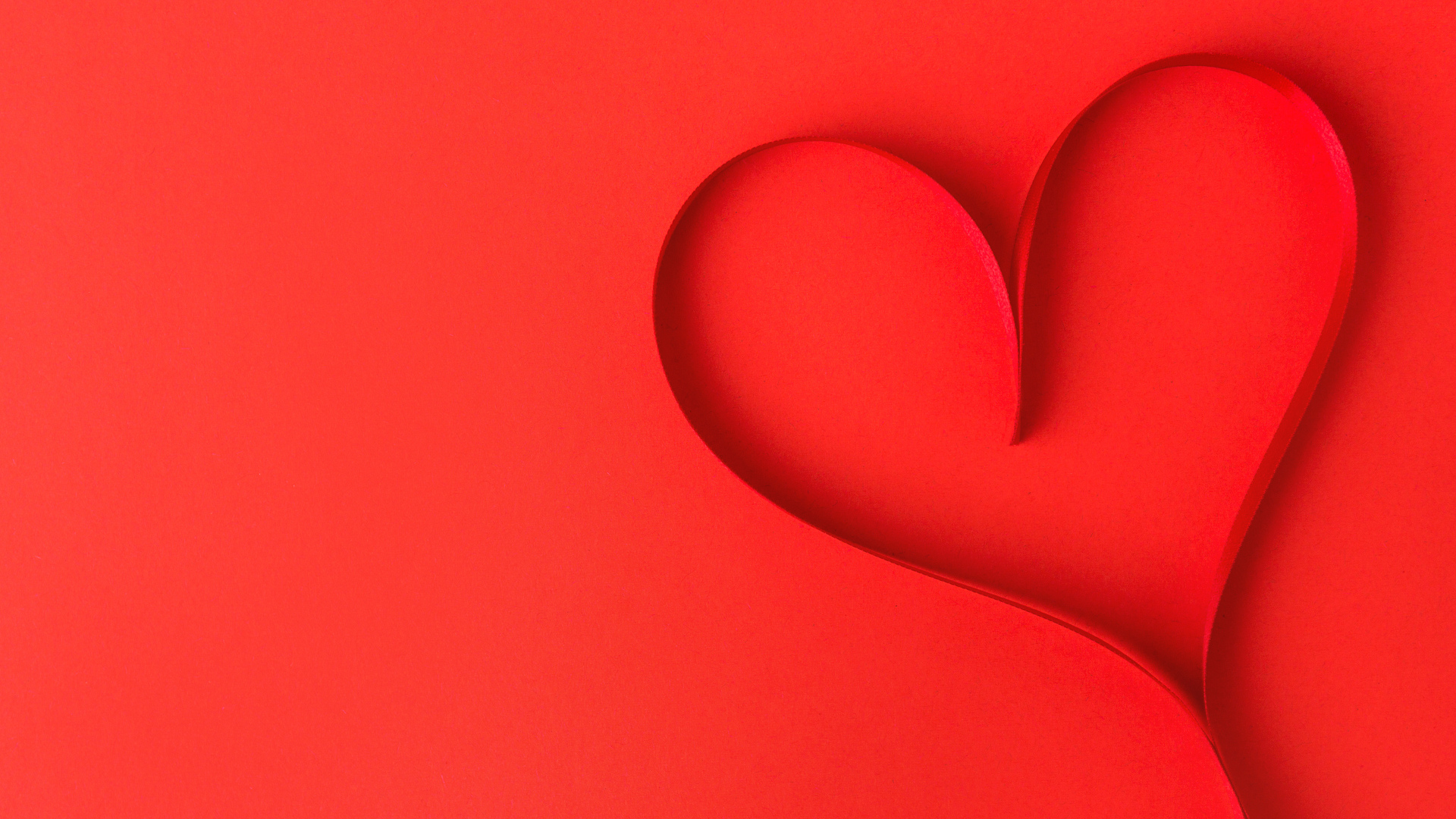 Сердце из атласной ленты на красном фоне