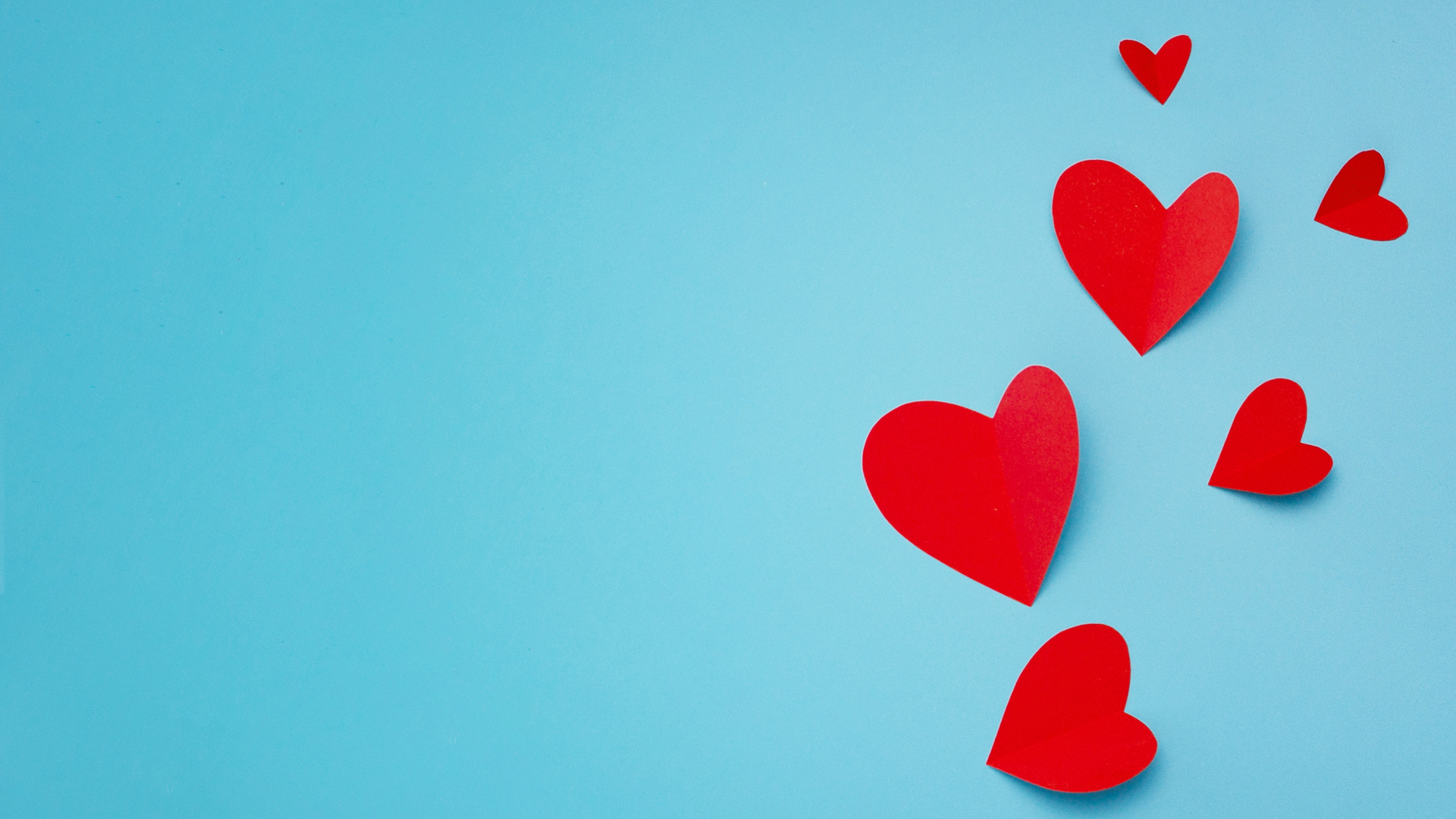Много красных бумажных сердечек на голубом фоне