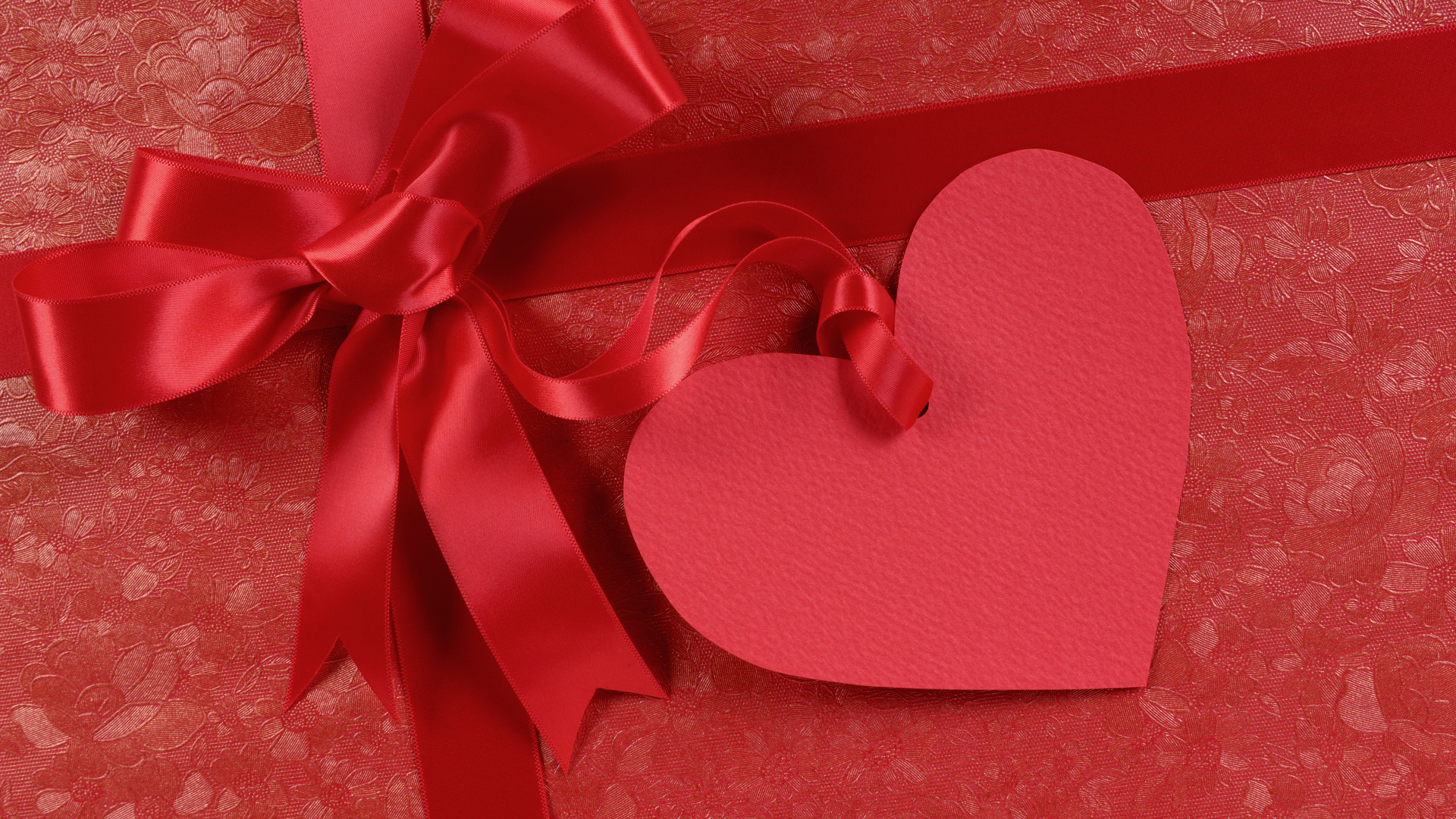 Paper heart with satin ribbon bow on red background