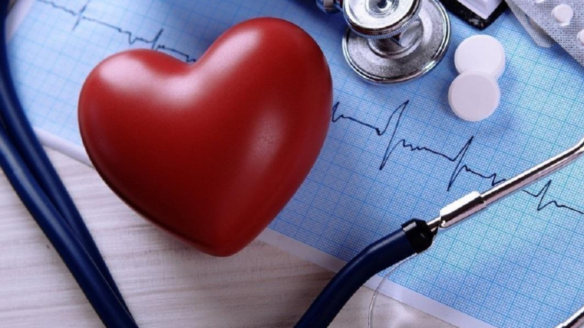 Красное сердце на столе с кардиограммой и стетоскопом