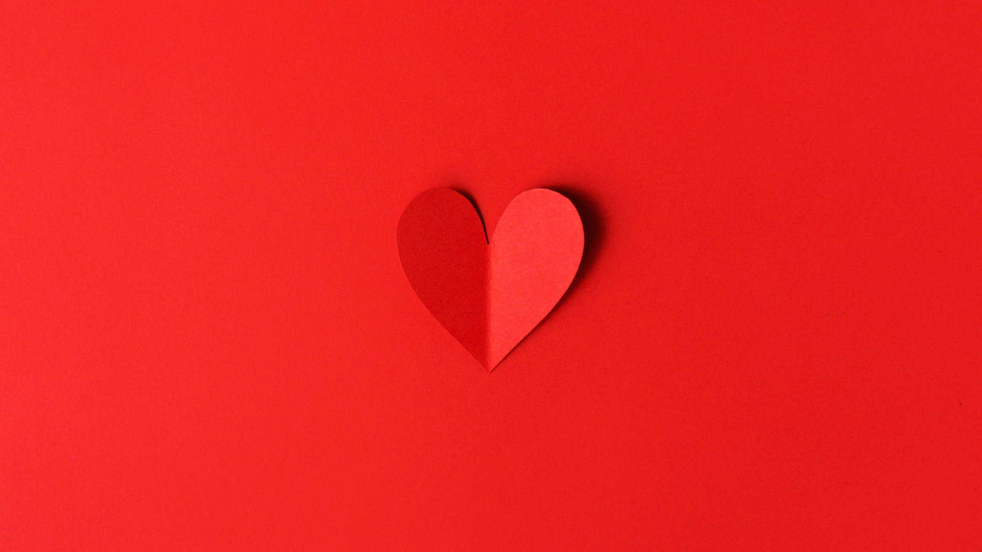 Маленькое бумажное сердце на красном фоне
